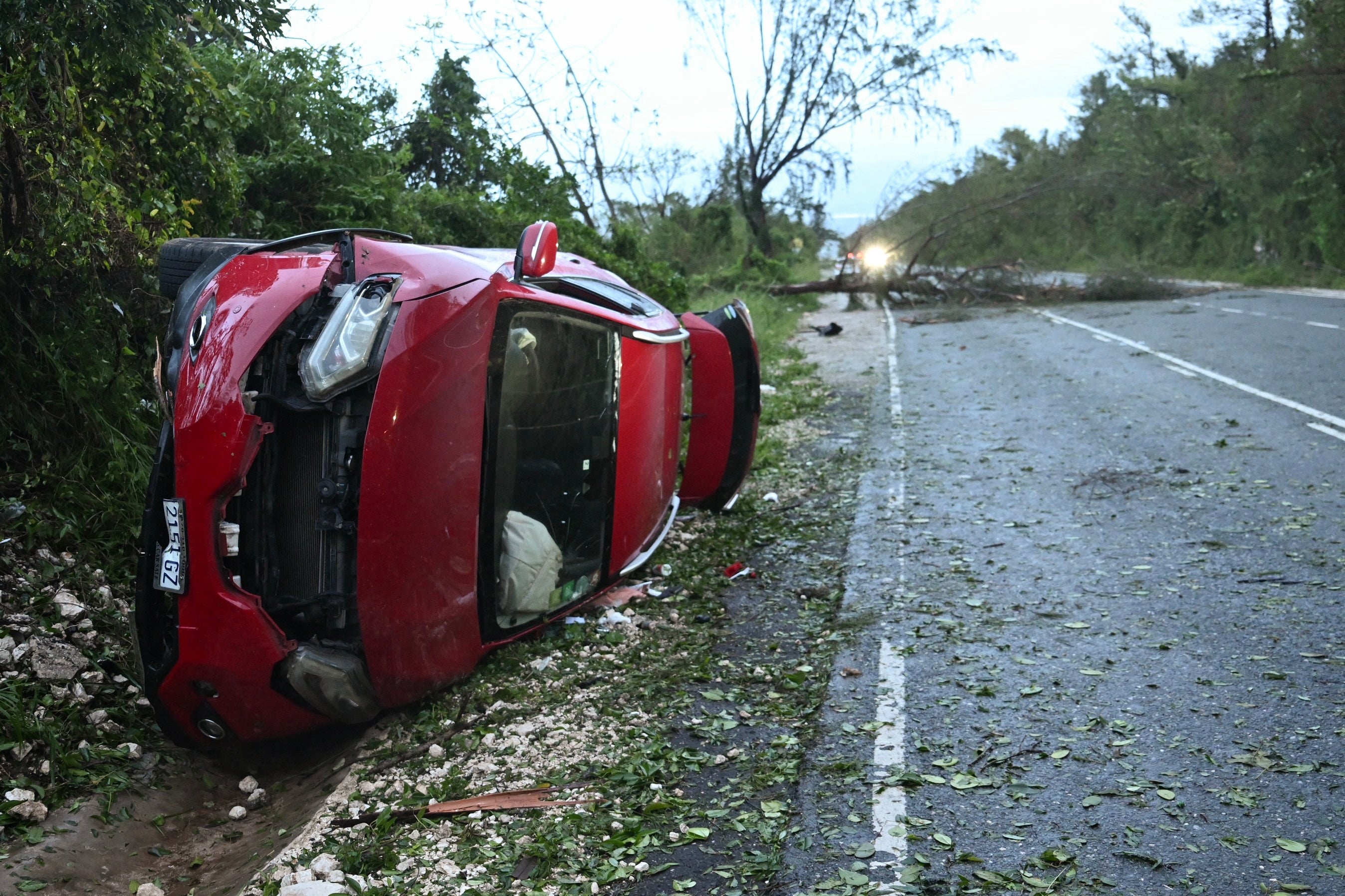 A damaged car by a fallen tree lay in the path of Hurricane Melissa