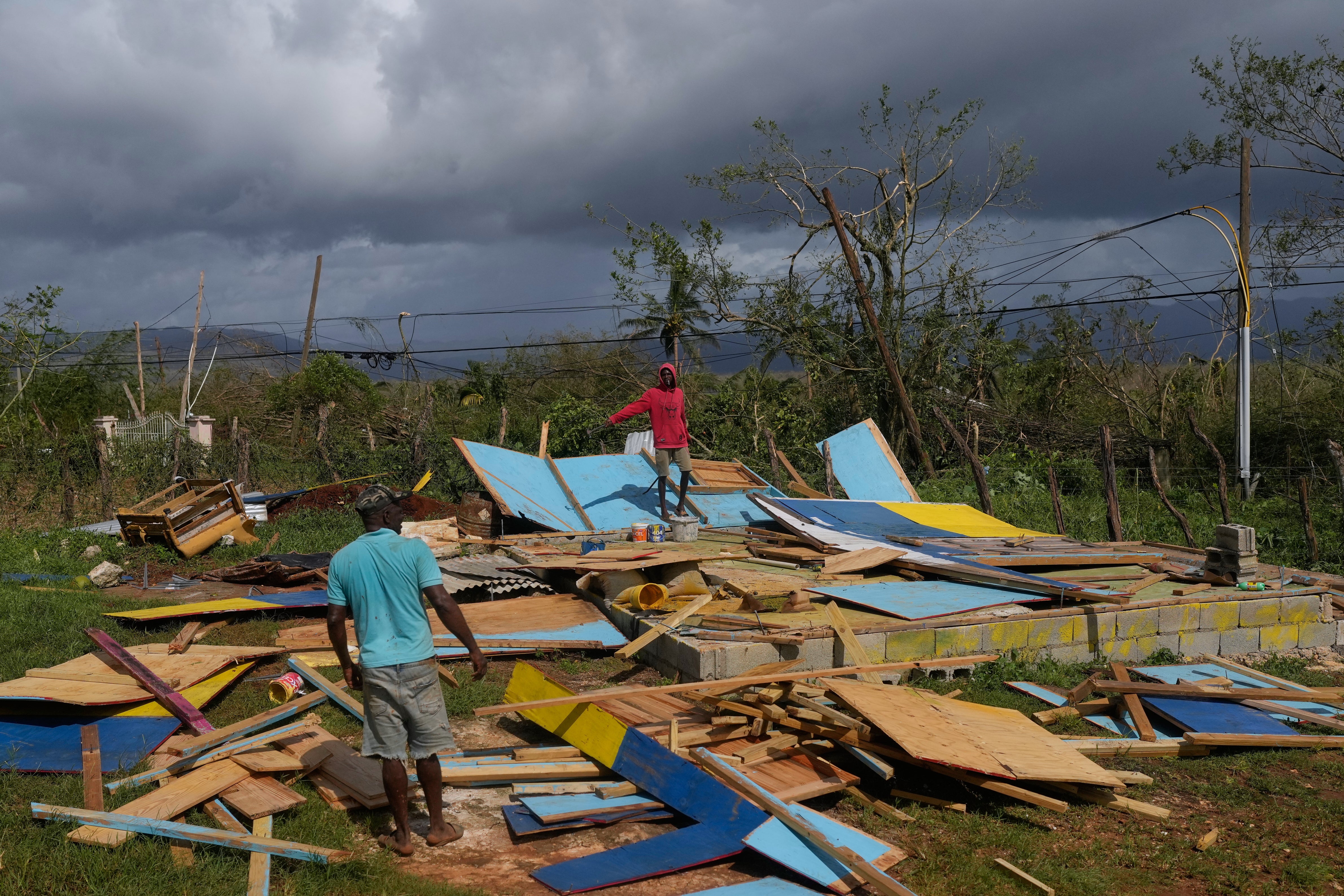 Residents stand on the wreckage of a house destroyed by Hurricane Melissa in Santa Cruz, Jamaica (Matias Delacroix/AP)