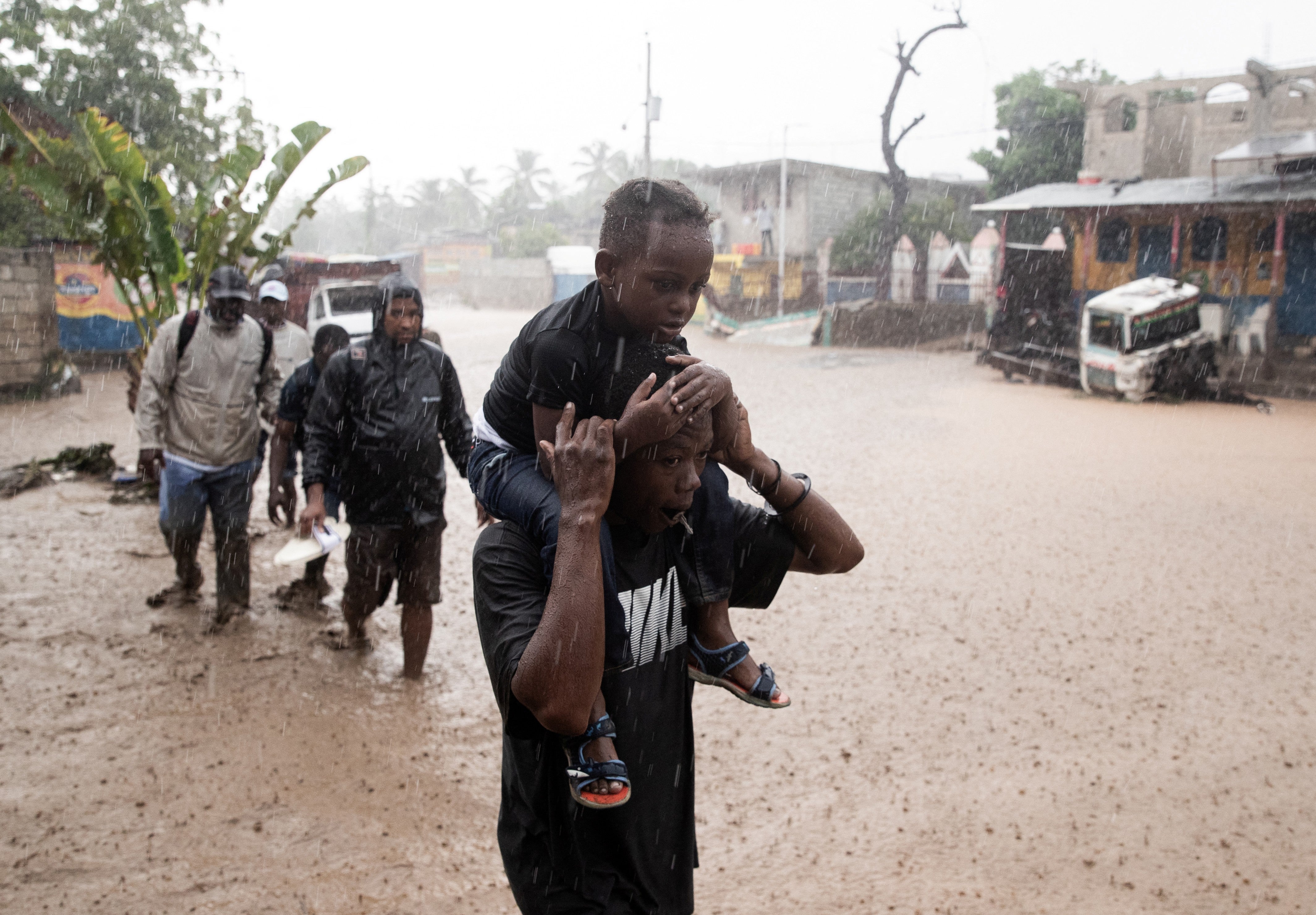 People walk through a flooded street Thursday in Petit-Goave, Haiti, following the passage of Hurricane Melissa. Much of the damage posed by hurricanes is related to precipitation, with warmer atmospheres able to hold more moisture