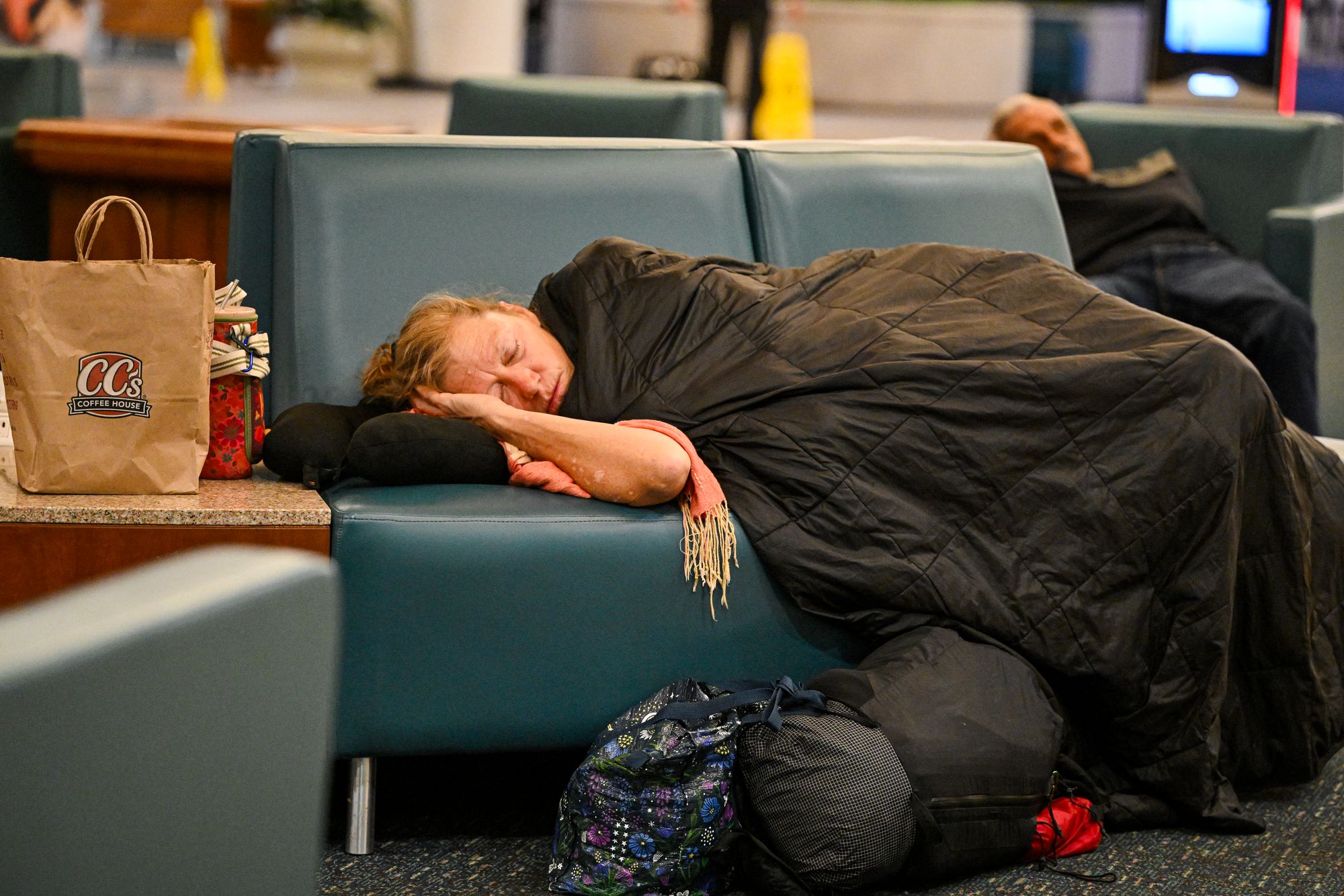 Travelers sleep on chairs at Orlando International Airport in Orlando on October 30