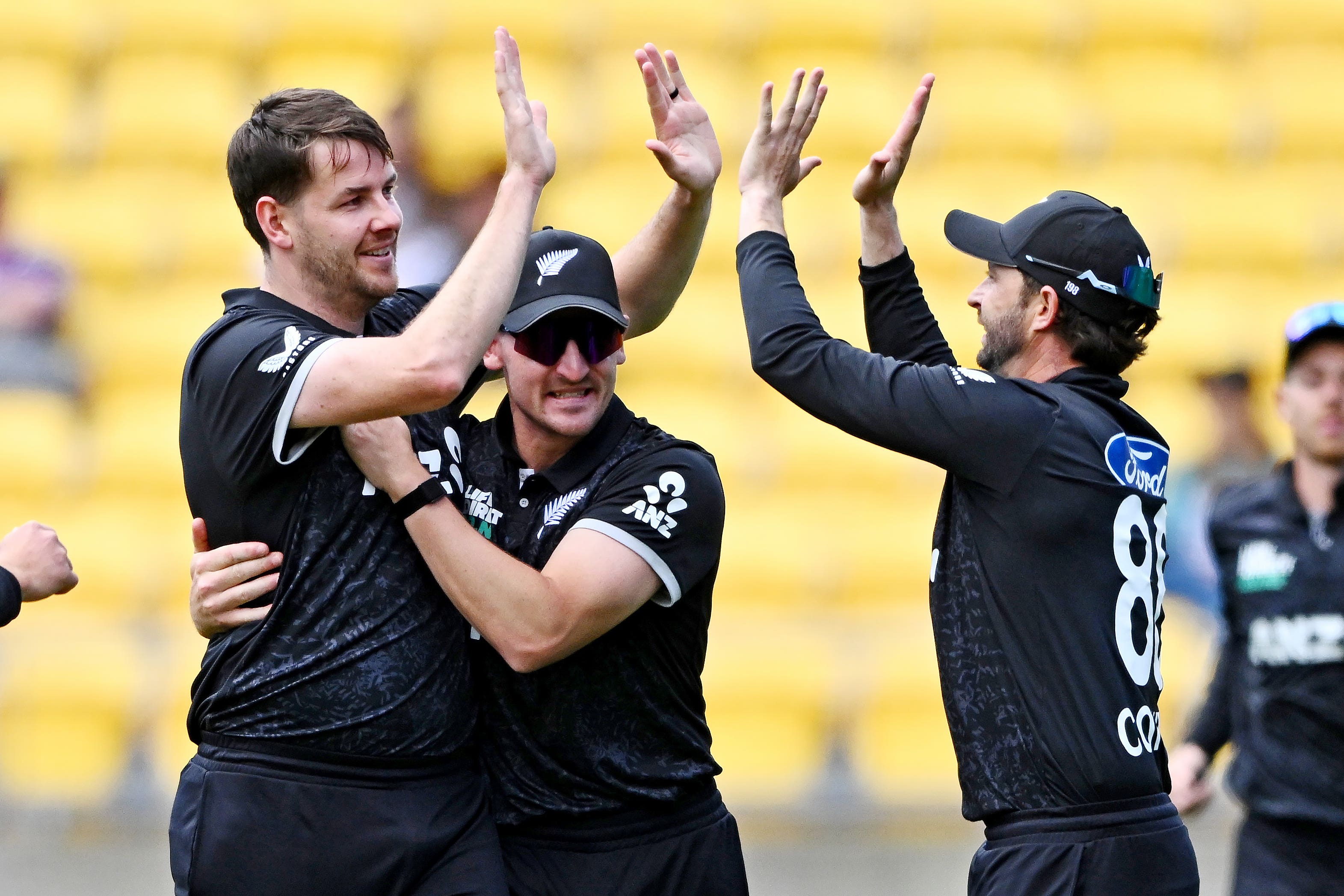 Jacob Duffy, left, Nathan Smith, and Devon Conway of New Zealand celebrate the wicket of Joe Root of England during the One Day International cricket match
