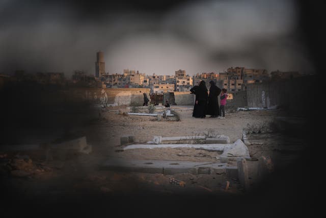 <p>Palestinian women stand at a cemetery in Khan Younis, where a makeshift camp is set up, in southern Gaza on 31 October 2025</p>