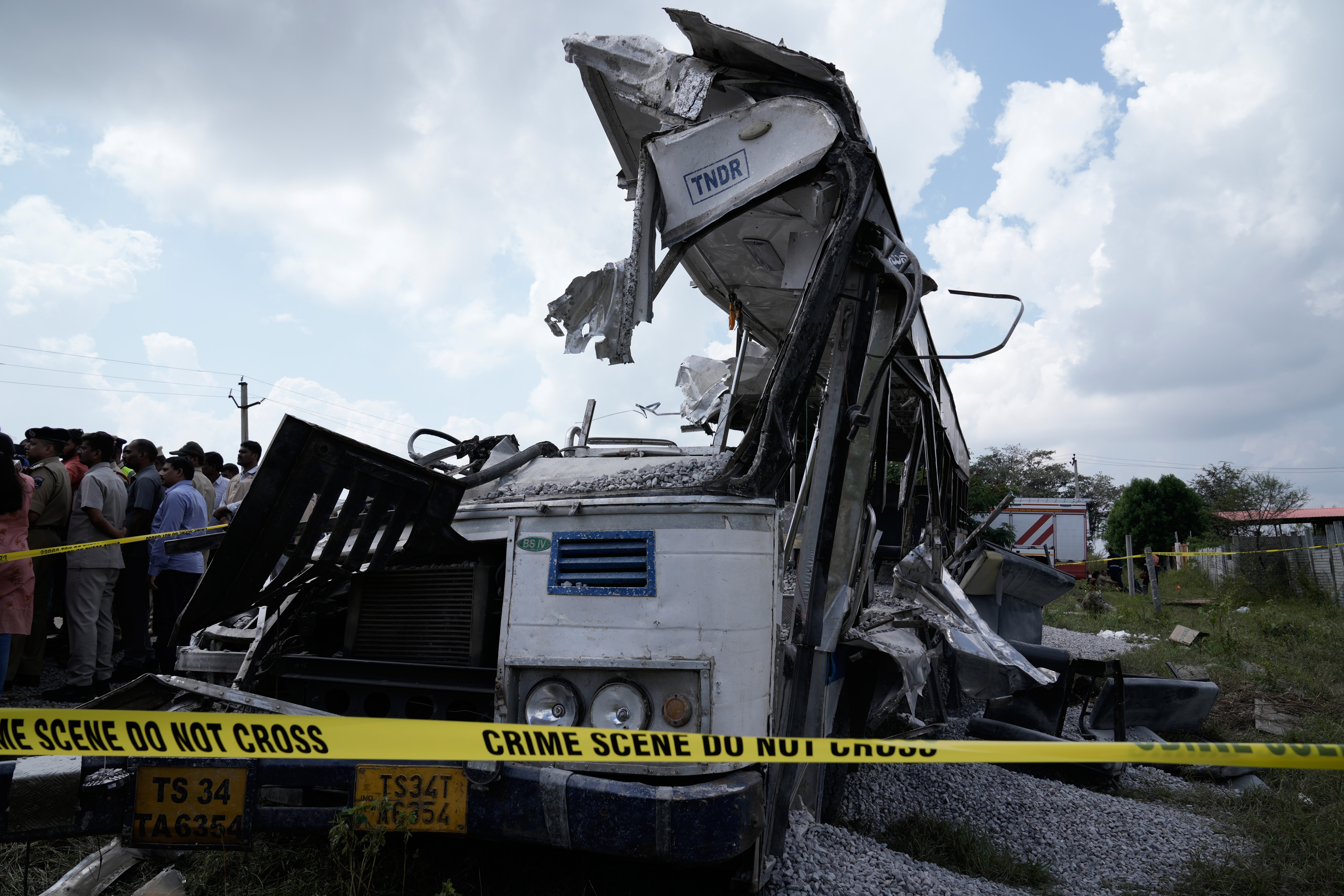 People stand next to the bus after a truck loaded with concrete stone chips rammed into it