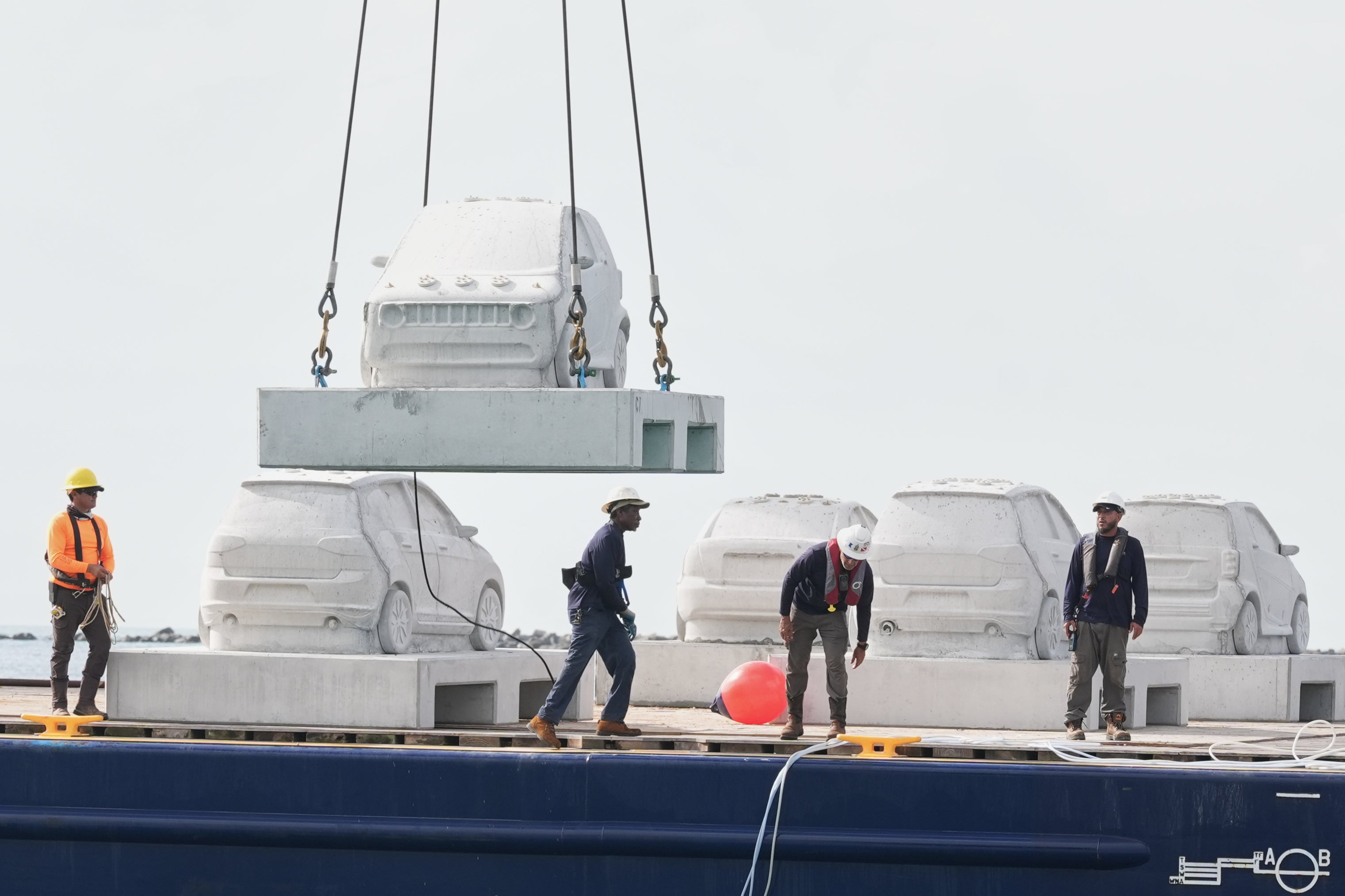 Workers prepare to submerge concrete cars that will be part of an underwater marine sculpture park off South Beach,Tuesday, Oct. 28, 2025, in Miami Beach, Fla. Native corals grown in a lab will be attached to the cars to create a reef