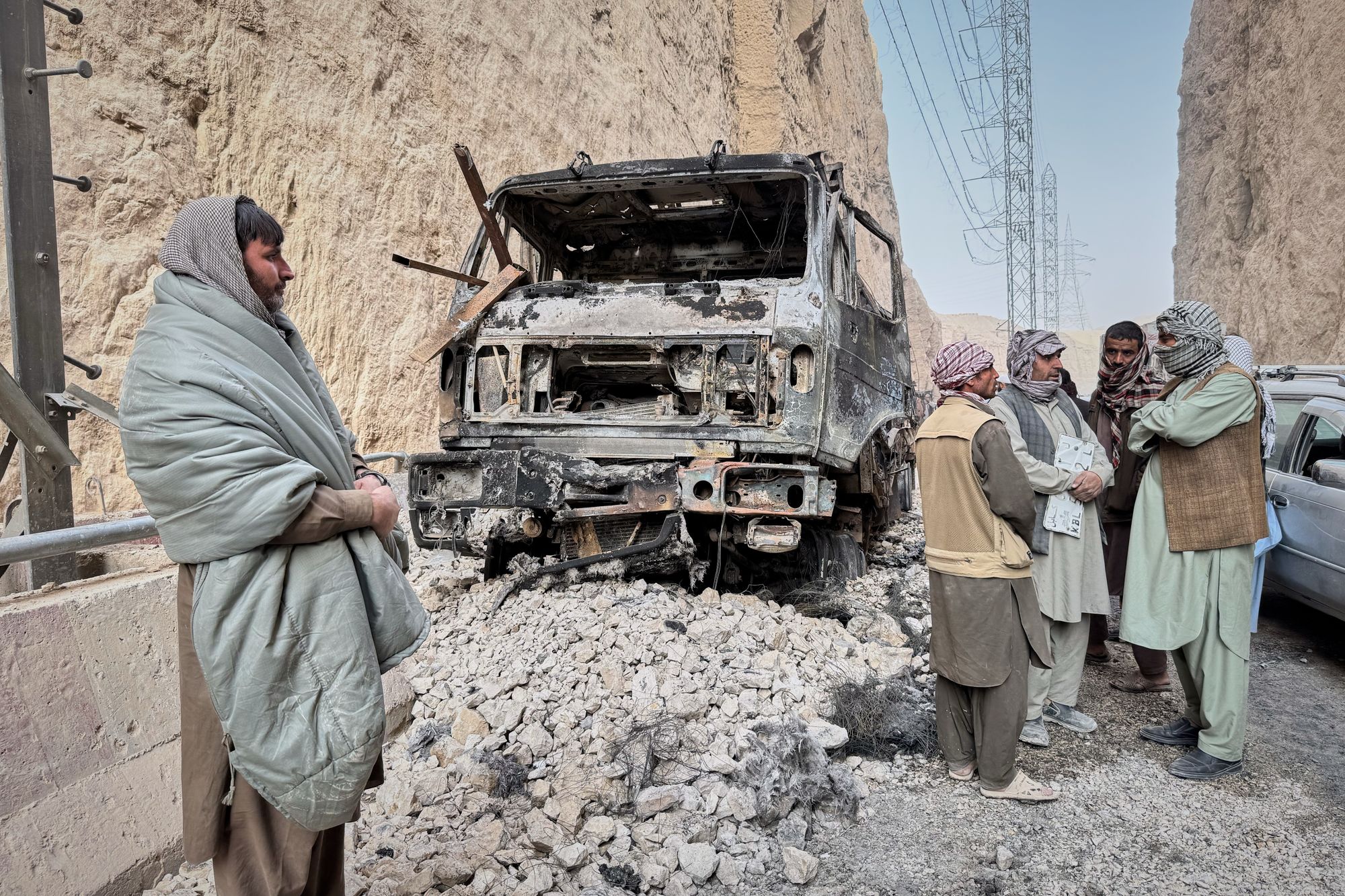 <p>Local officials confer next to a burned-out truck that caught fire from power cables as they try to reach affected areas during a powerful 6.3-magnitude earthquake in a rural part of the Khulm District in Samangan Province, northern Afghanistan</p>