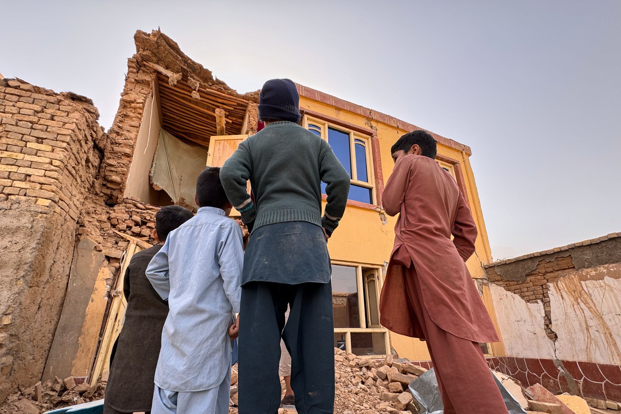 Local children look at a destroyed house after a powerful 6.3-magnitude earthquake in a rural area of the Khulm District in Samangan Province, northern Afghanistan,