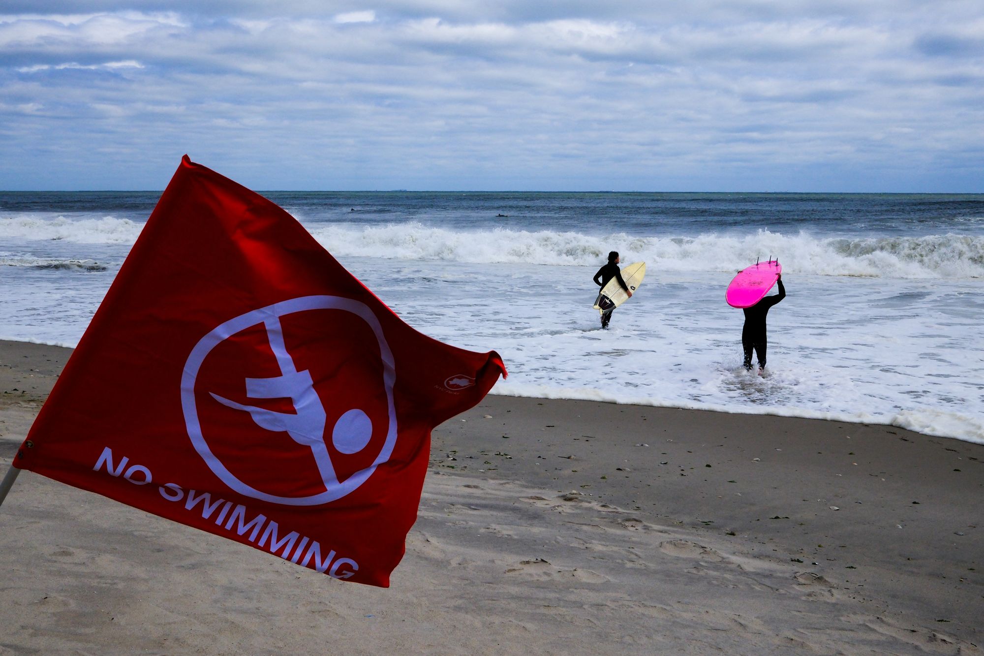 Surfers wade into the water at Rockaway Beach, New York in August. Most of the storm-related impacts to the U.S. this year were rough surf, rip currents and rain