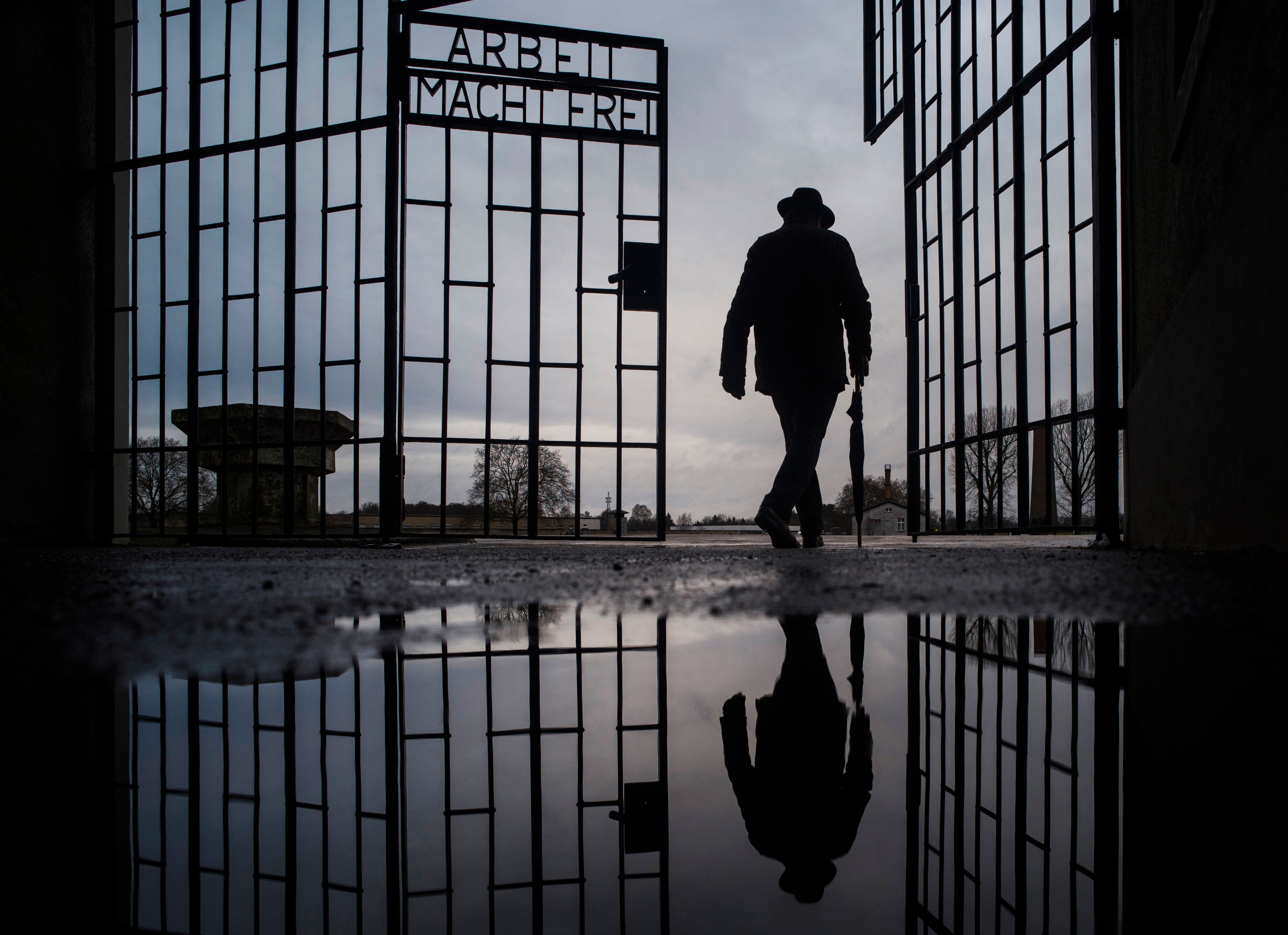 A man walks through the gate of the Sachsenhausen Nazi death camp with the phrase 'Arbeit macht frei' (work sets you free) at the International Holocaust Remembrance Day, in Oranienburg, about 30 kilometers, (18 miles) north of Berlin, Germany, Jan. 27, 2019