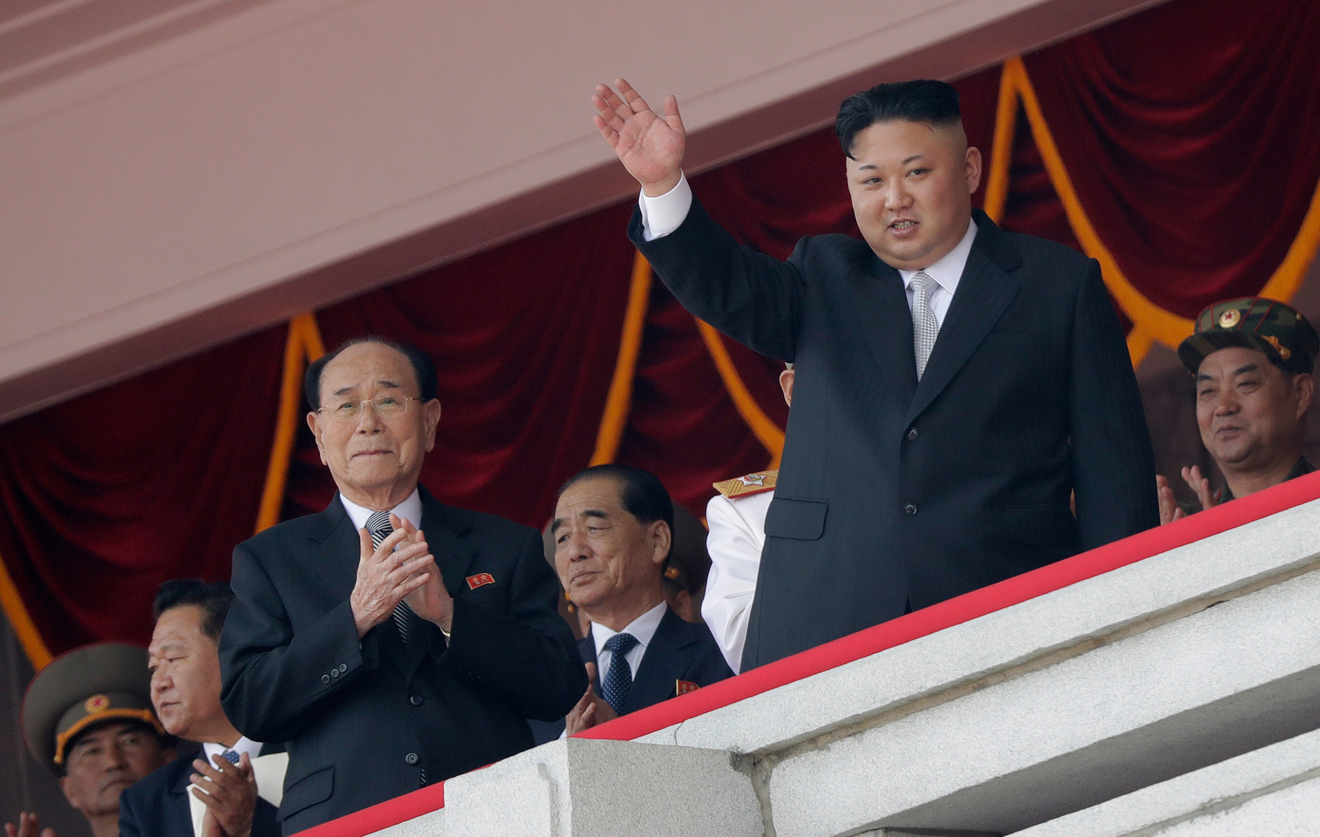 File: North Korean leader Kim Jong Un, right, waves while Kim Yong Nam, third left, Choe Ryong Hae, second left, and Pak Pong Ju, center, clap during a military parade 15 April 2017, in Pyongyang