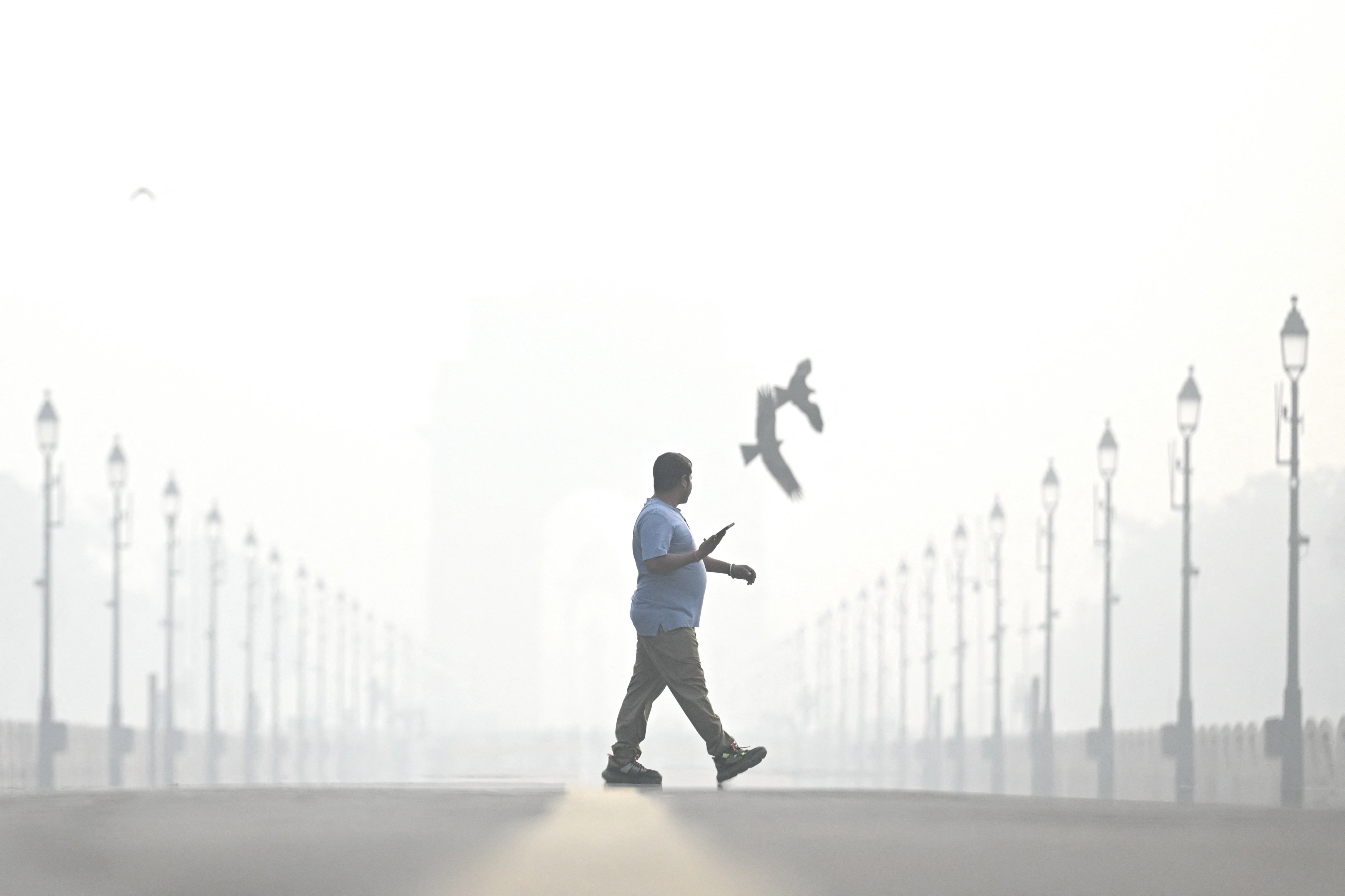 A man walks amid smoggy conditions near India Gate in Delhi on 29 October 2025