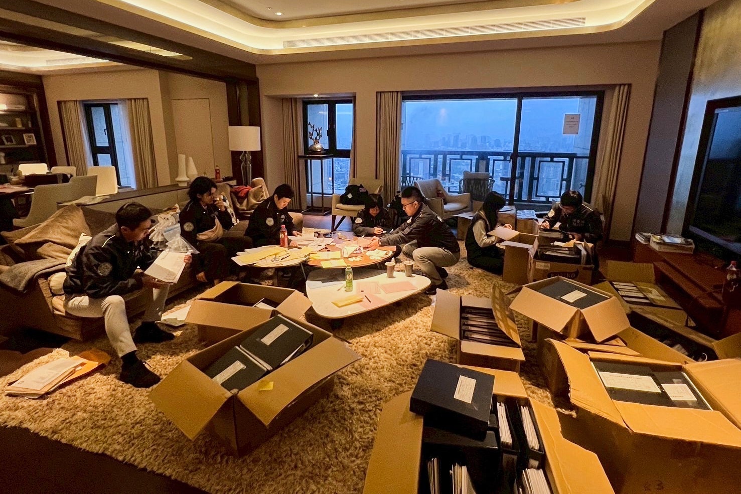Investigation Bureau agents check documents after they seized an apartment which belongs to the suspected head of a criminal scamming syndicate, in Taipei, Taiwan