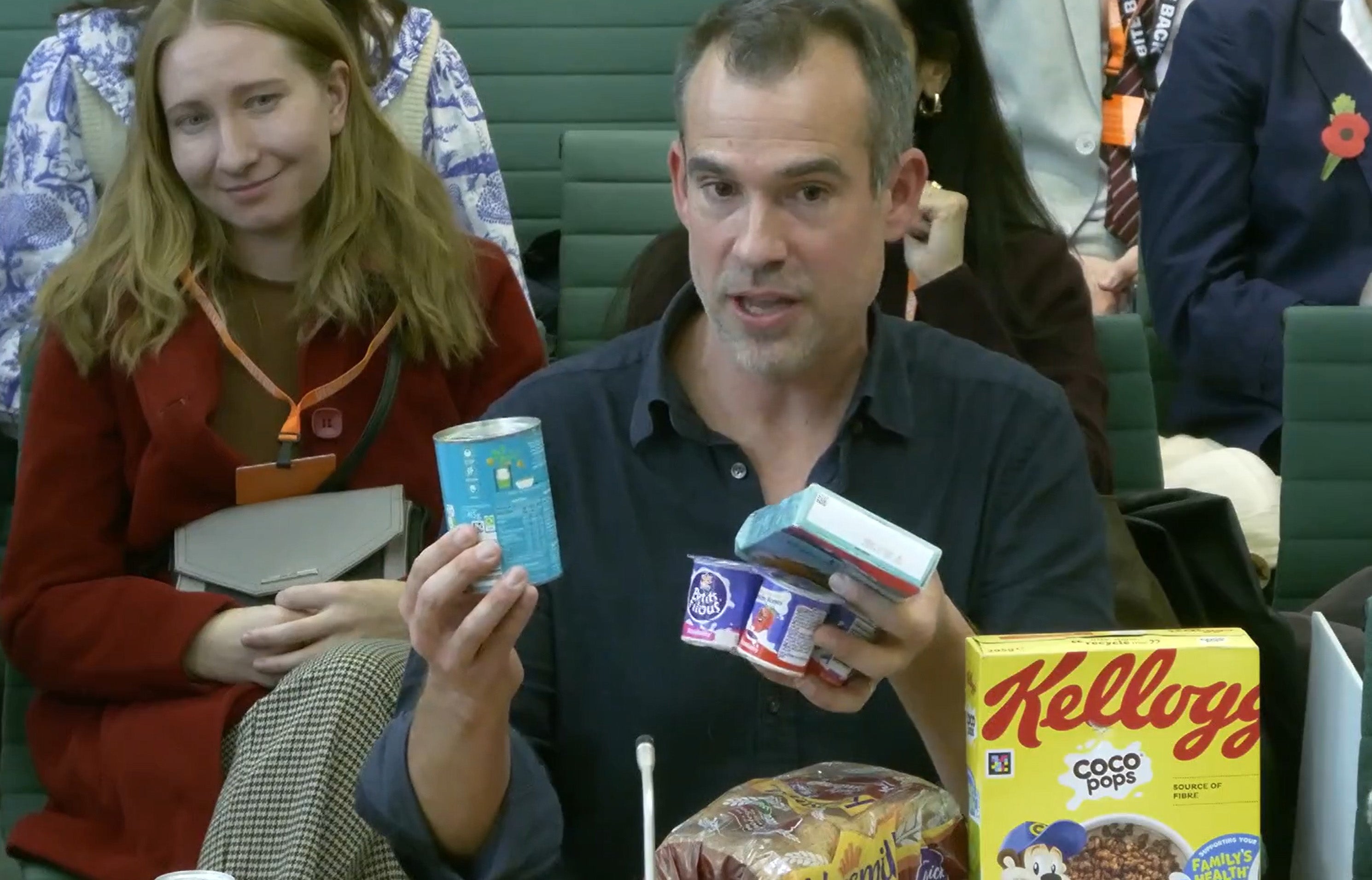 Chris van Tulleken, professor of global health at University College London and a BBC TV doctor, holding food items as he appeared before the Health and Social Care Committee at the House of Commons