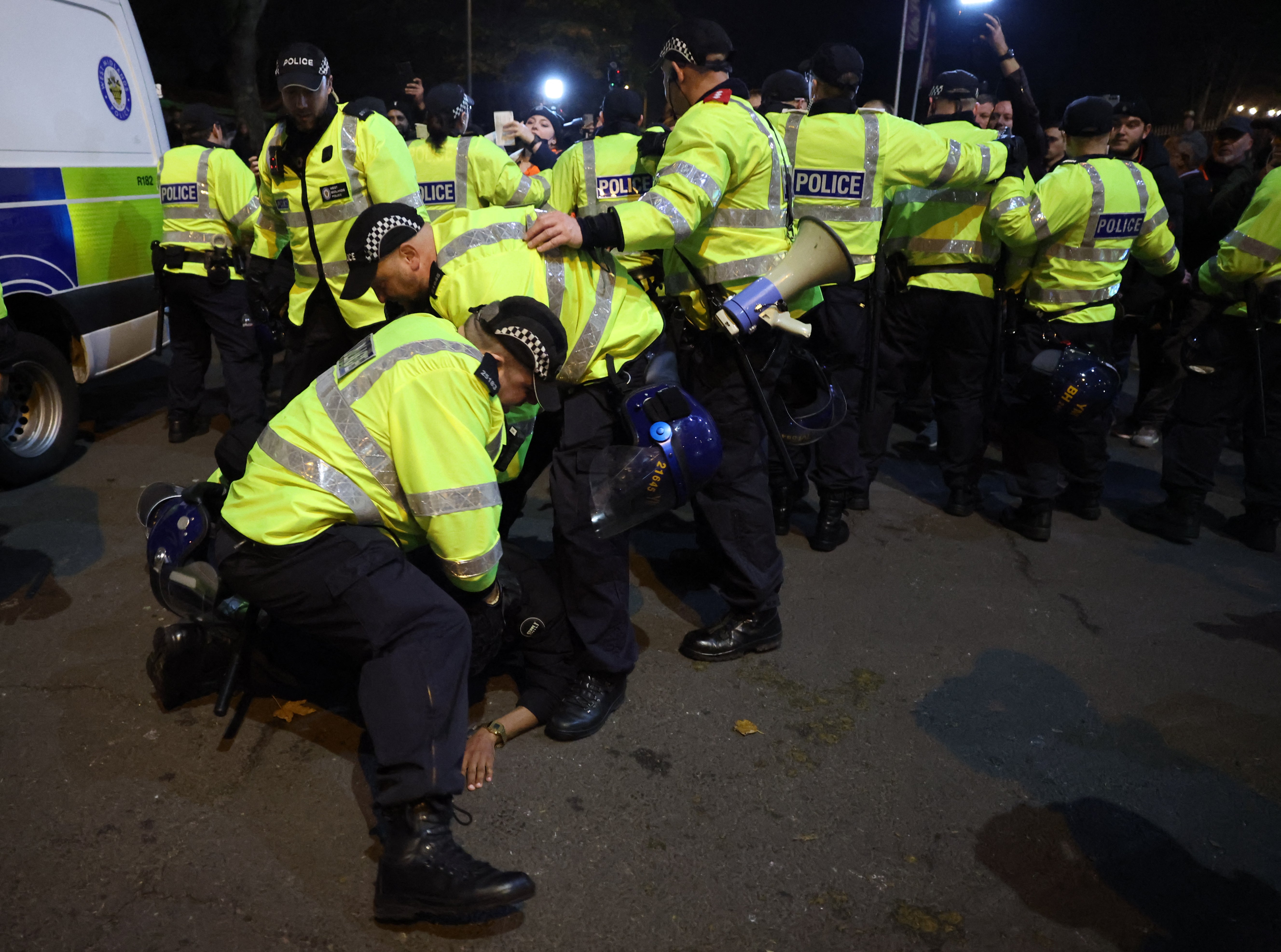 Police officers detain a protester outside the stadium during the match