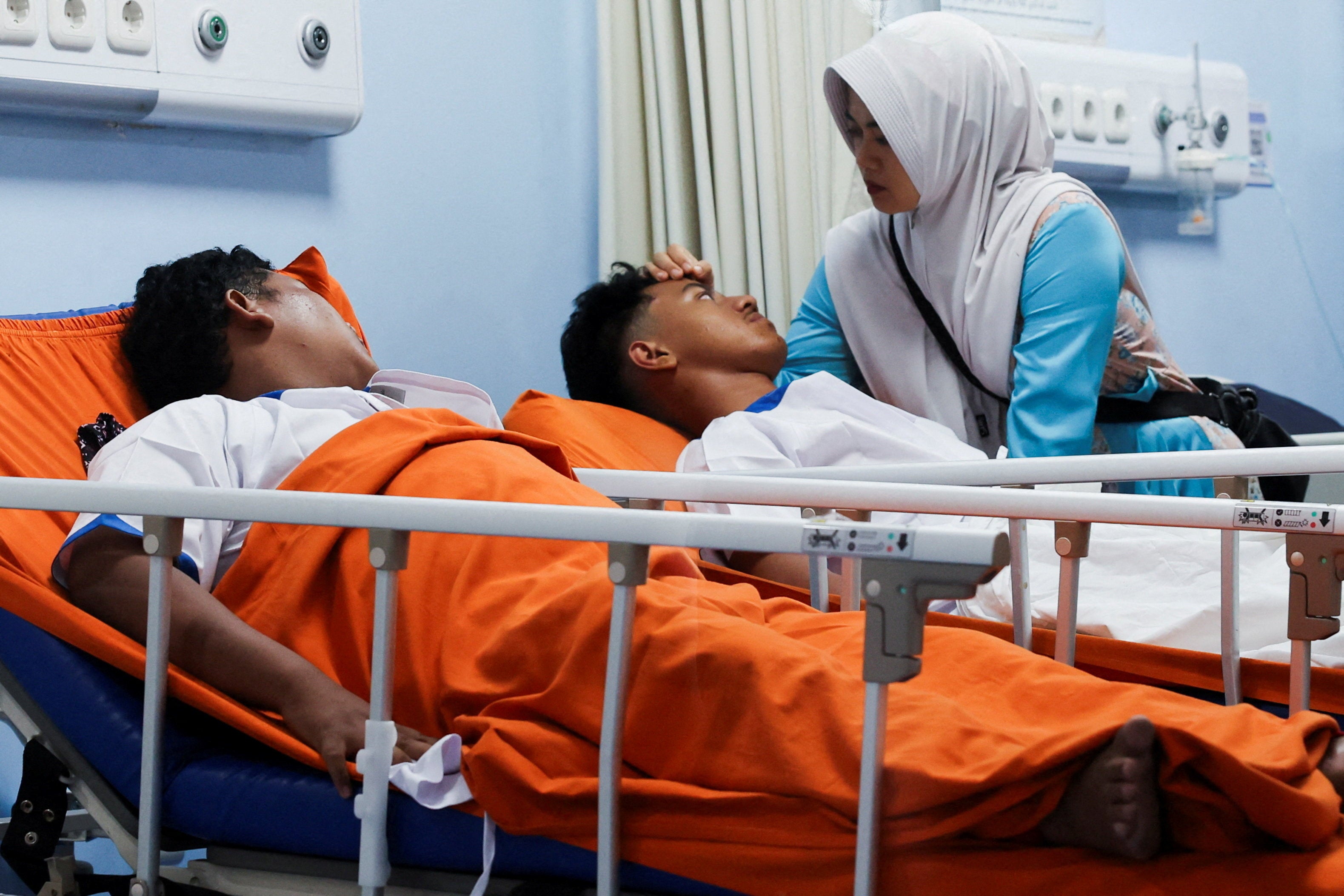 A relative gestures while injured students lie at Jakarta Islamic hospital after an explosion occurred during Friday prayers at a mosque inside a school complex in Jakarta