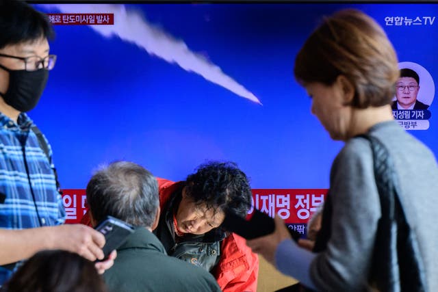 <p>People walk past a TV screen showing file footage of a North Korean missile test, at a railway station in Seoul, South Korea, on 7 November 2025</p>