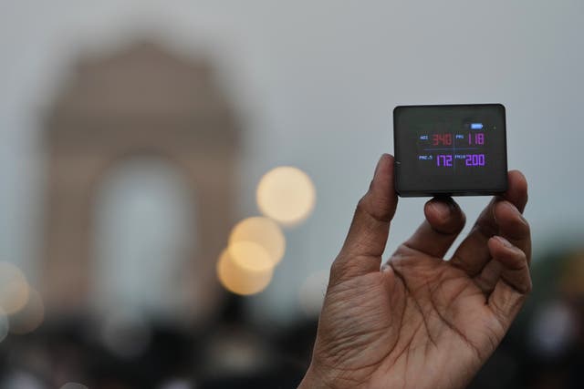<p>A protester shows the present AQI or Air Quality Index during a protest against what they called the government's lack of action to combat air pollution in the capital city Delhi</p>