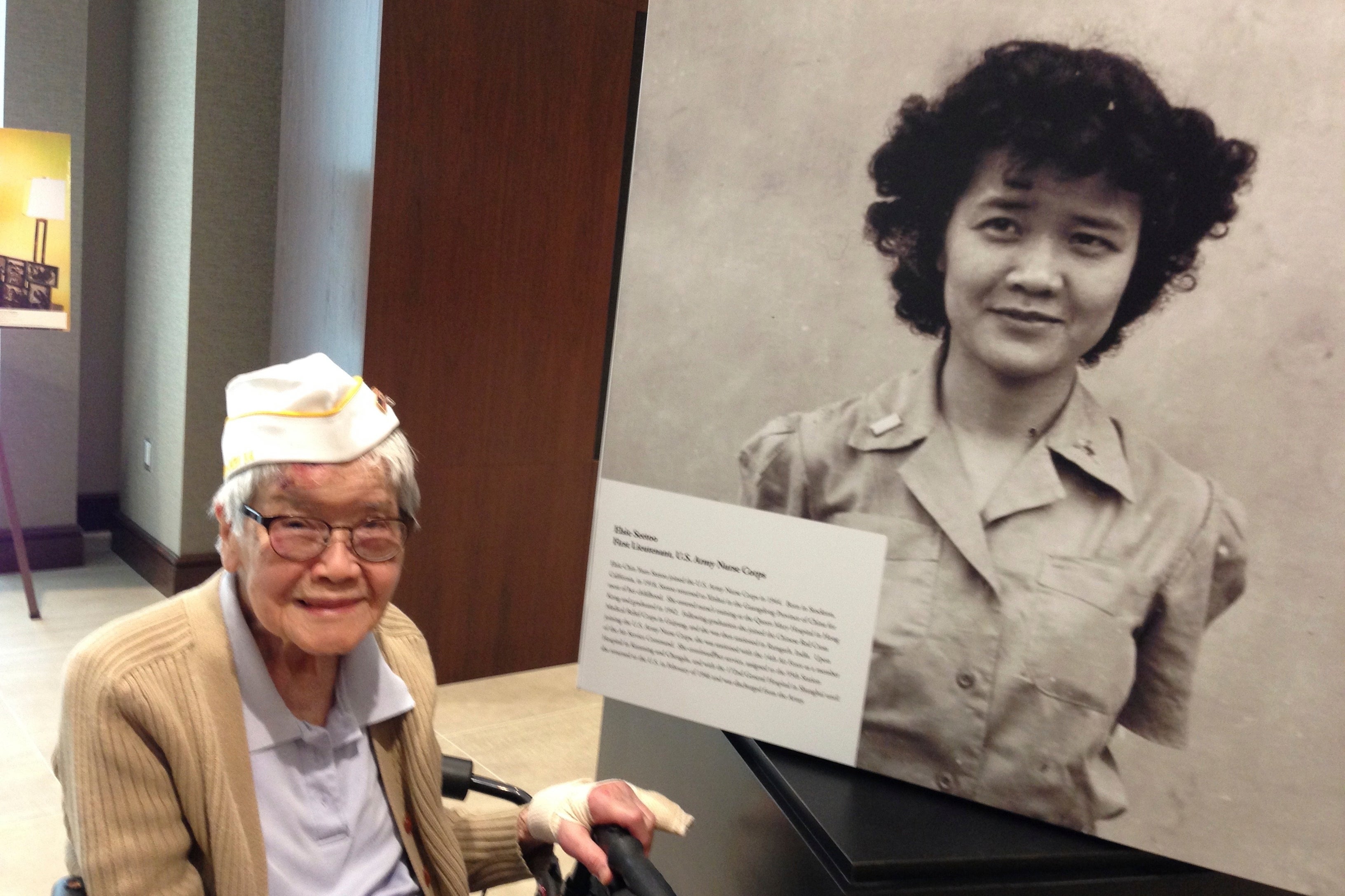 This photo provided by Elaine Yuen shows her mother, Elsie Chin Yuen Seetoo, next to a photo of herself at an exhibit at the Army Historical Foundation in Arlington, Va., in May 2017