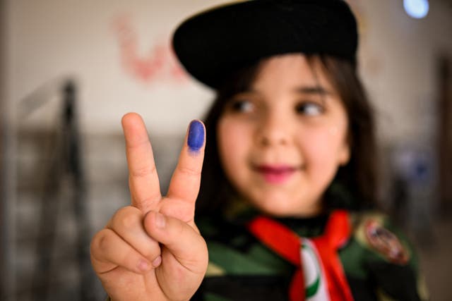 <p>An Iraqi girl poses with an ink-marked index finger at a polling station in the southern city of Basra during the historic Iraq elections</p>