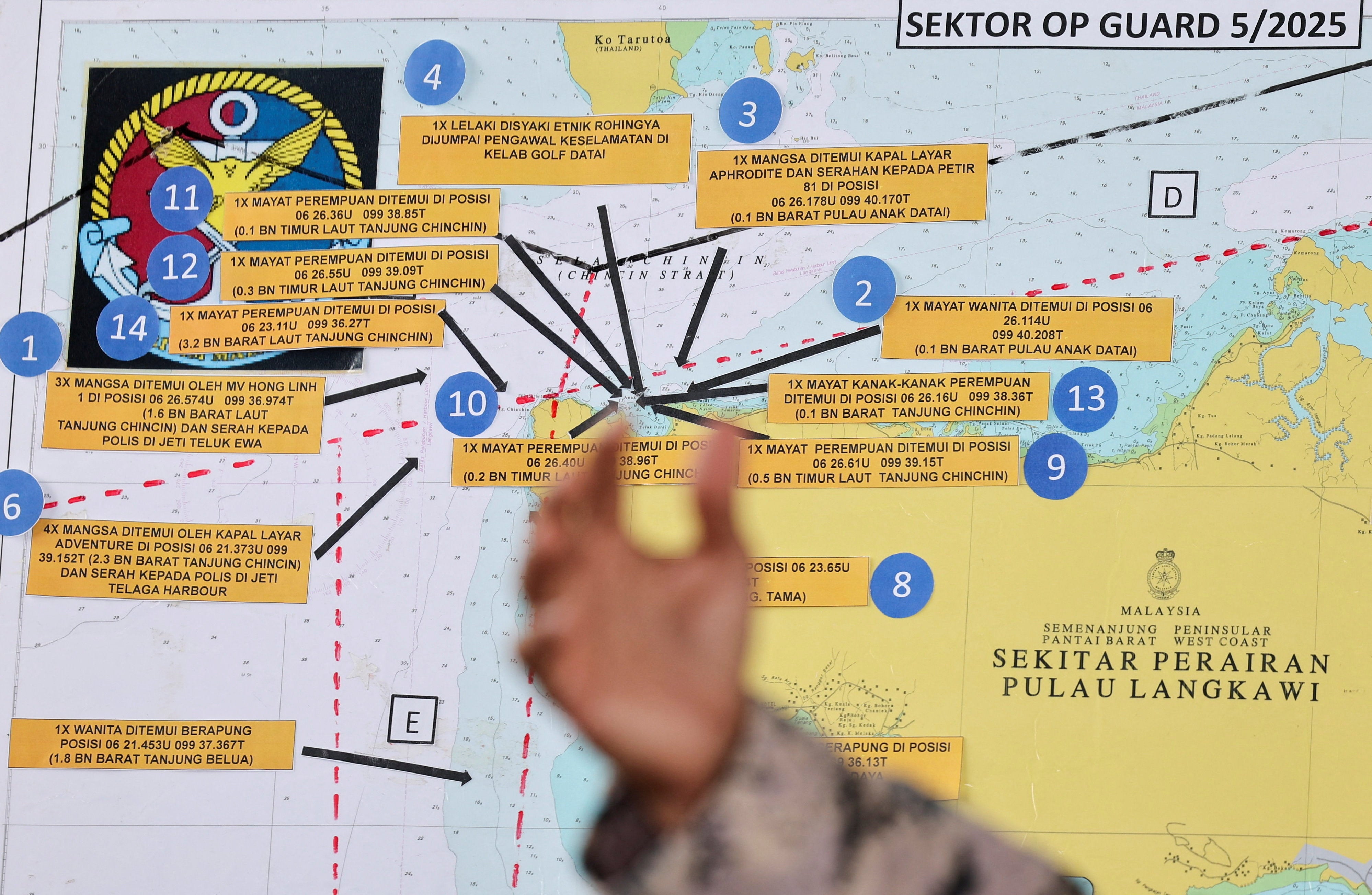 2025 年 11 月 10 日，一艘载有缅甸受迫害罗兴亚人社区成员的船只在马来西亚兰卡威附近泰国-马来西亚边境附近的水域沉没，一名马来西亚海事执法机构官员在一张地图旁边打手势，该地图指向受害者被发现的地区
