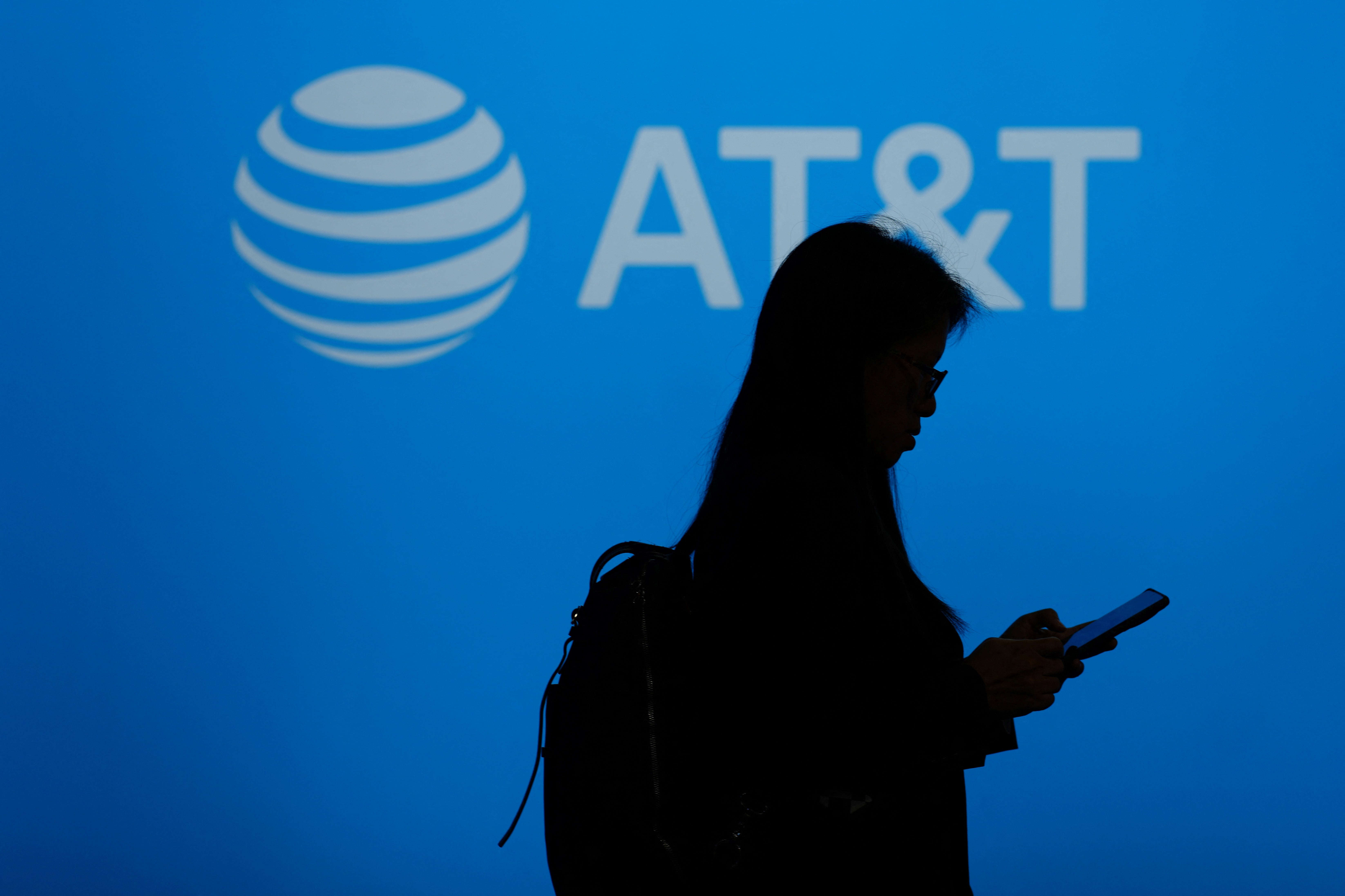 A visitor walks past US multinational telecommunications AT&T logo during the Mobile World Congress (MWC), the telecom industry's biggest annual gathering, in Barcelona on February 26, 2024. The world's biggest mobile phone fair throws open its doors in Barcelona with the sector looking to artificial intelligence to try and reverse declining sales