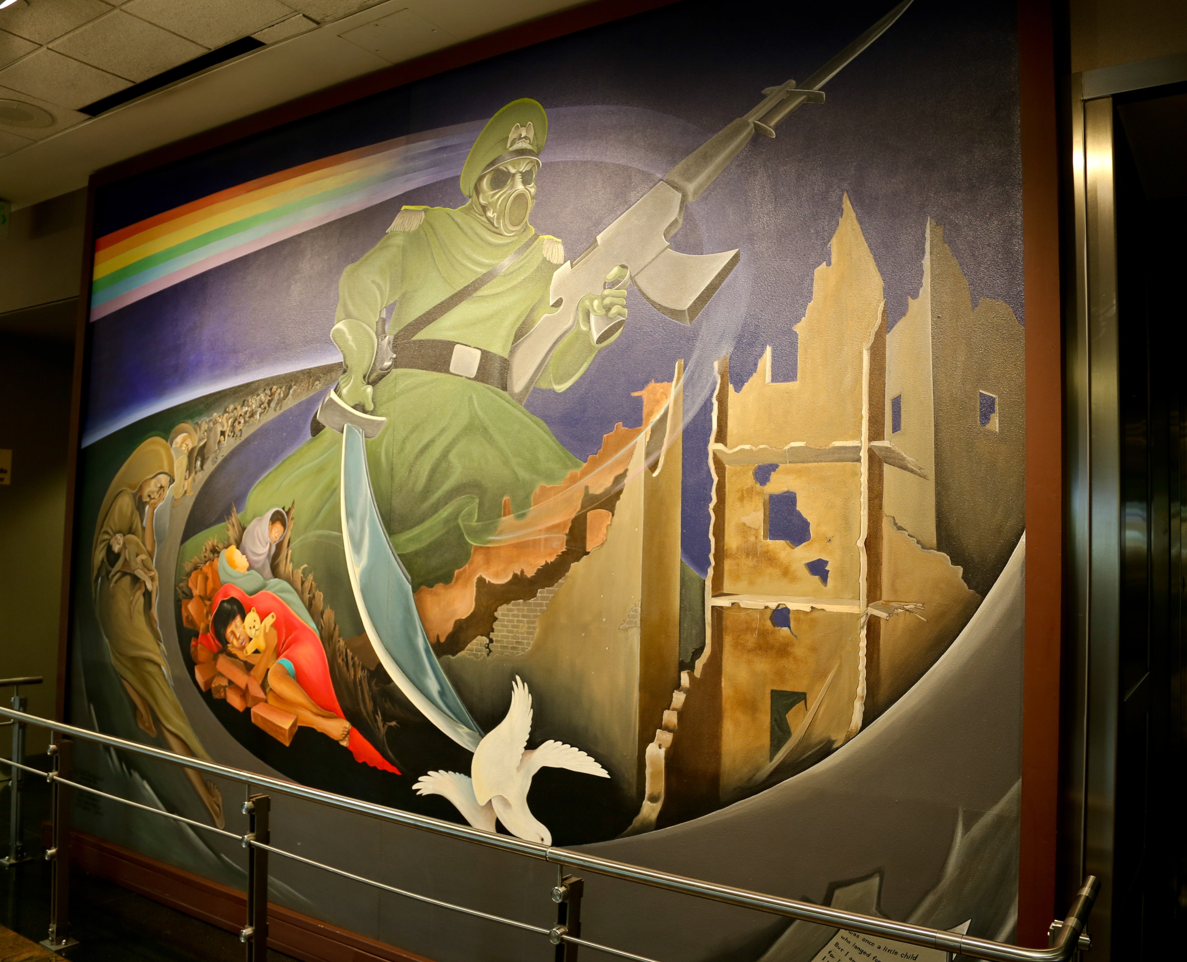In one part of the mural, a soldier in a gas mask holds a sword over a dead dove as children cower nearby