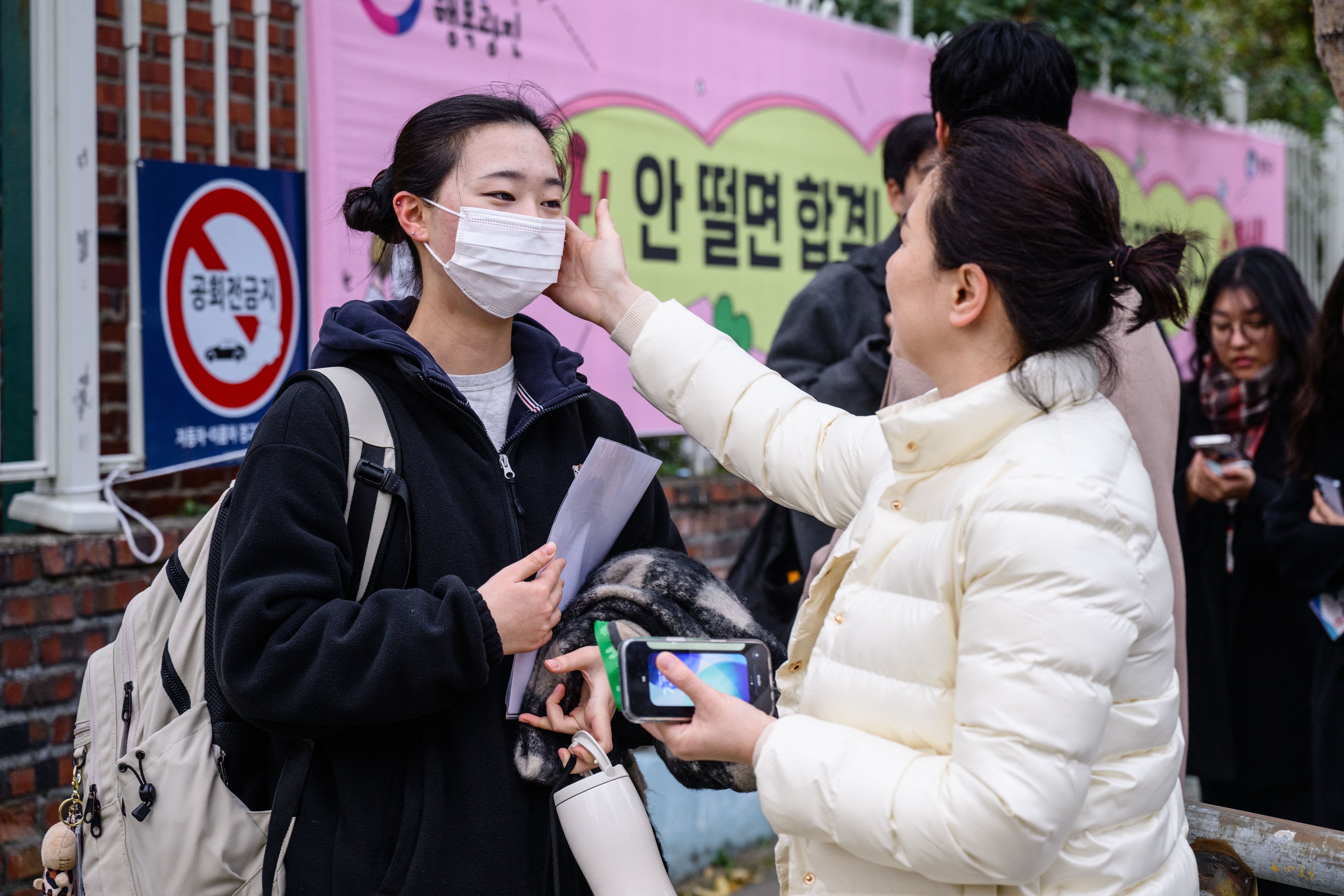 A student (L) speaks to her relative as she arrives for the annual college entrance exam, known locally as Suneung, outside the Gwangnam High School in Seoul on 13 November