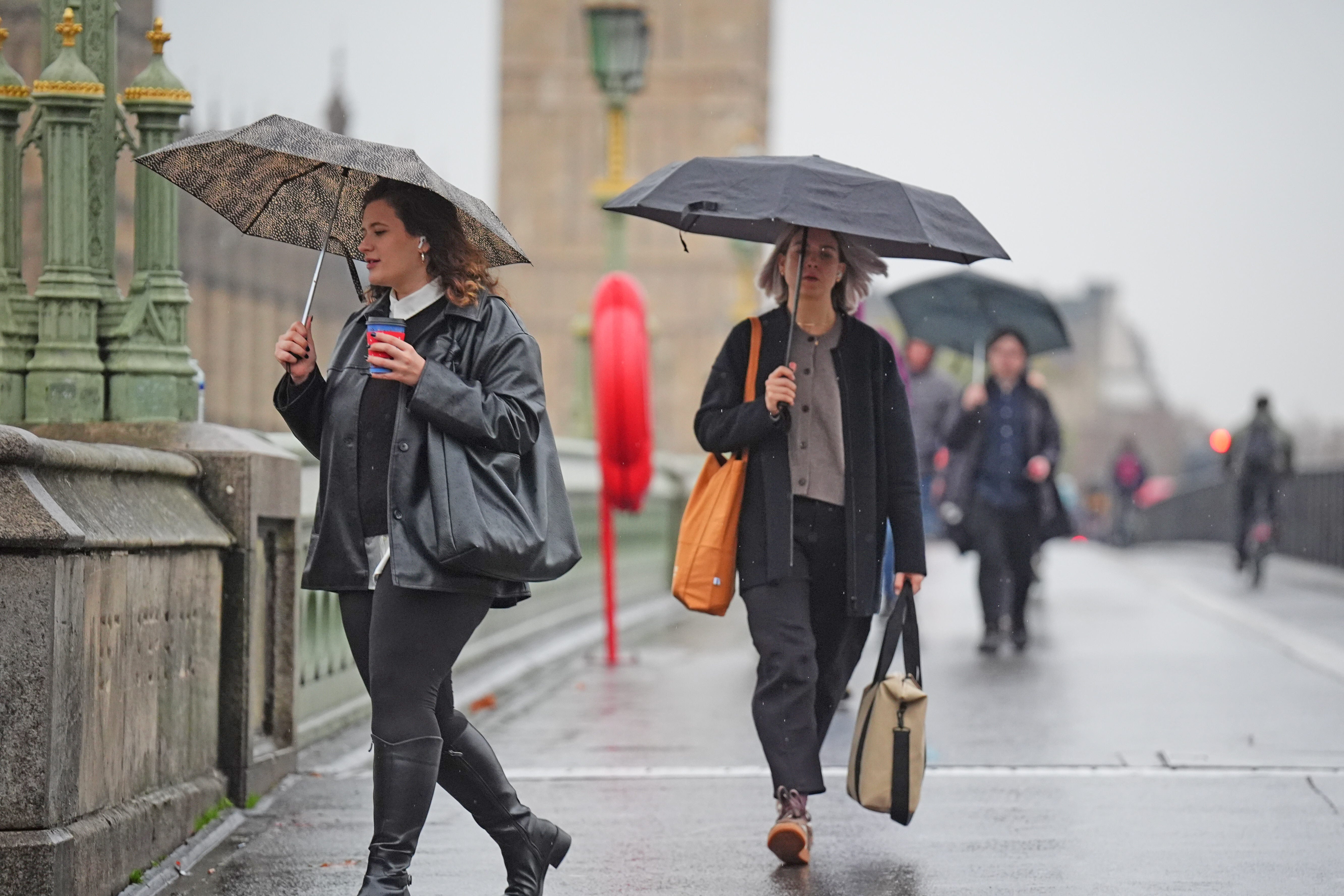 People walk in the rain across Westminster Bridge in central London (James Manning/PA)