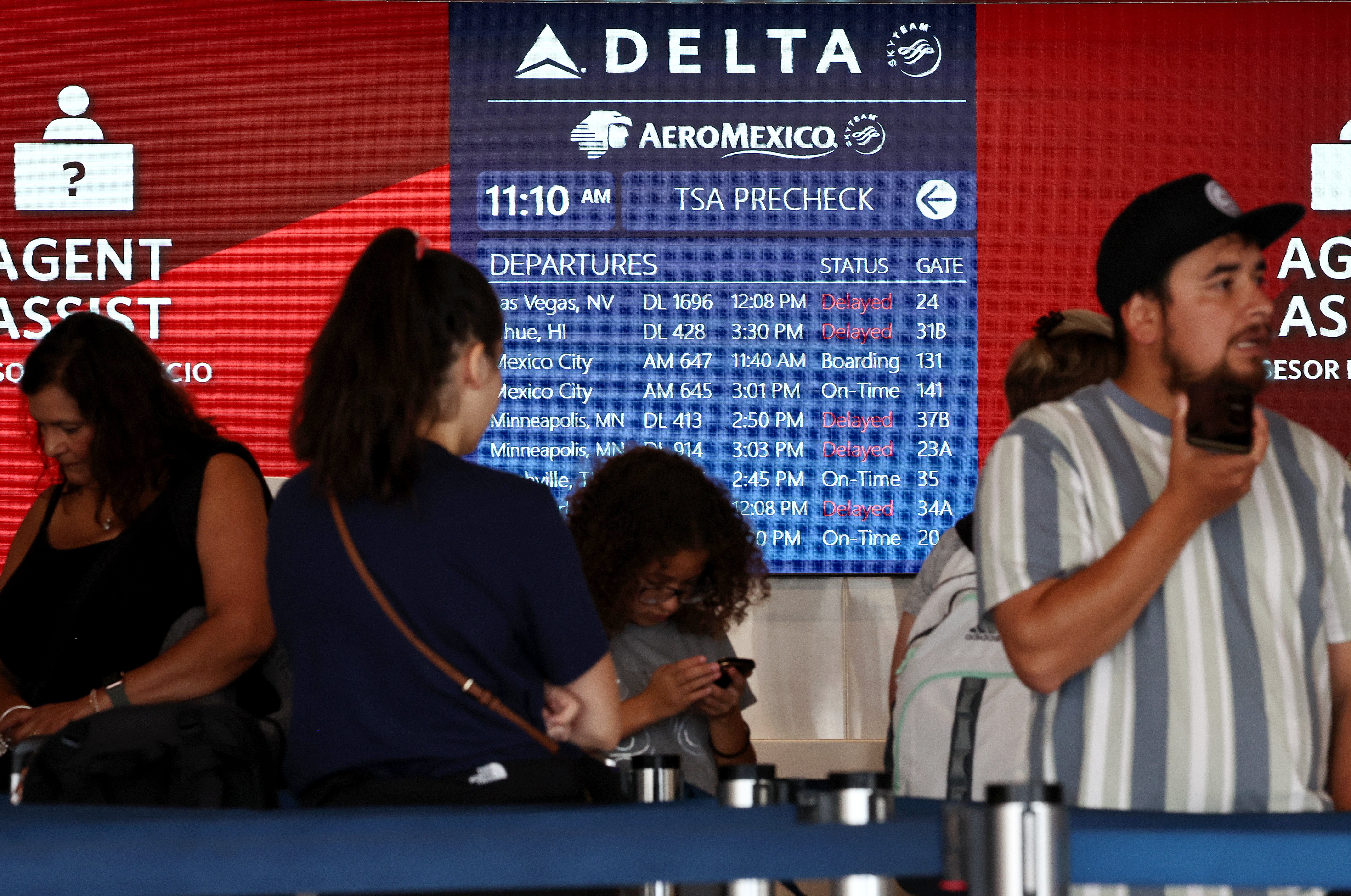 LOS ANGELES, CALIFORNIA - JULY 23: Travelers wait in line, as a flight board shows delays, on the check-in floor of the Delta Air Lines terminal at Los Angeles International Airport (LAX) on July 23, 2024 in Los Angeles, California. Delta Air Lines is still reeling in the aftermath of the CrowdStrike outage with 24 flights cancelled and 27 flights delayed at LAX today and 434 cancelled Delta flights nationwide today
