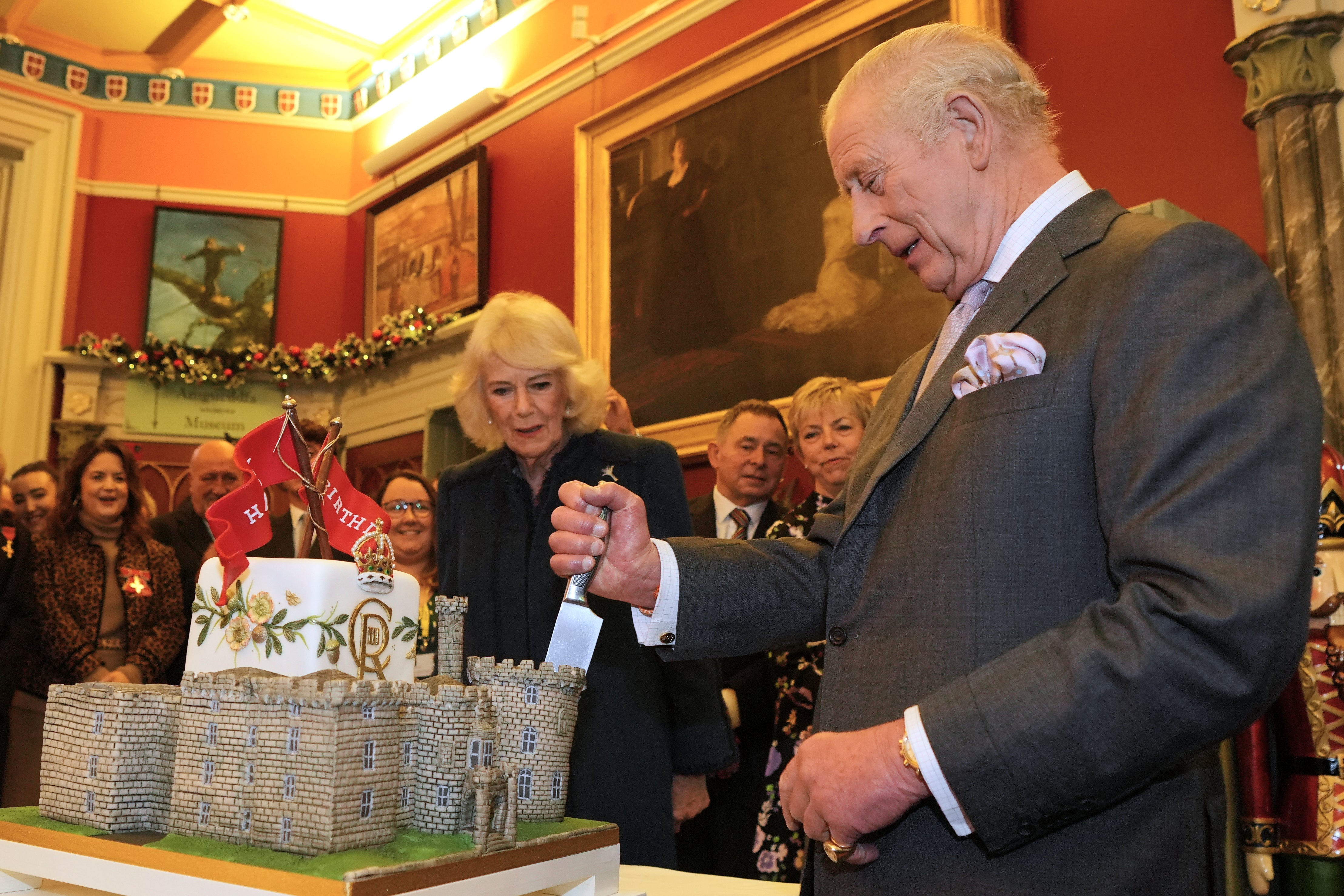 The King cuts a cake shaped as a castle to mark his 77th birthday (Kin Cheung/PA)