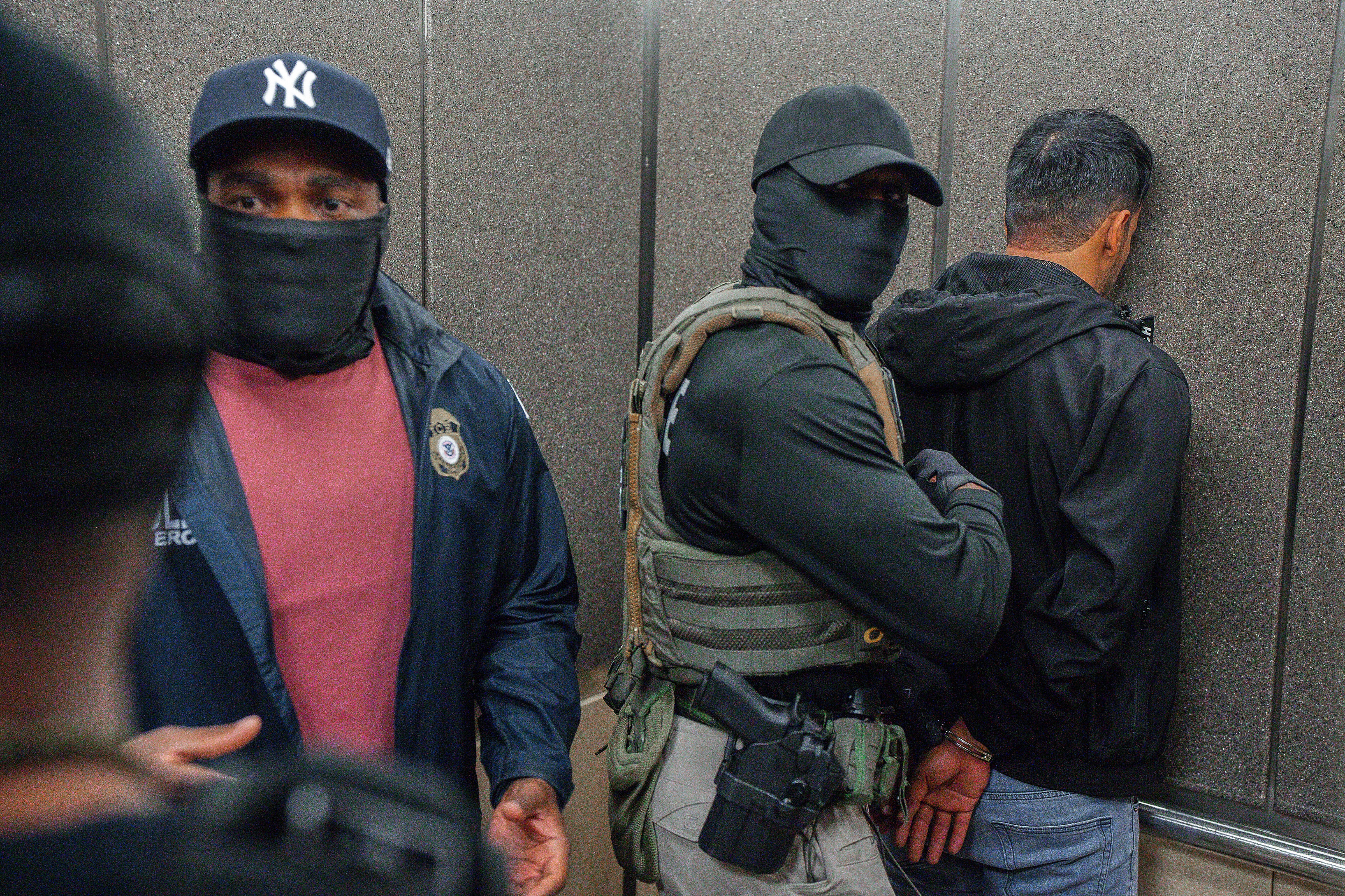 Immigration and Customs Enforcement (ICE) agents escort a detained immigrant into an elevator