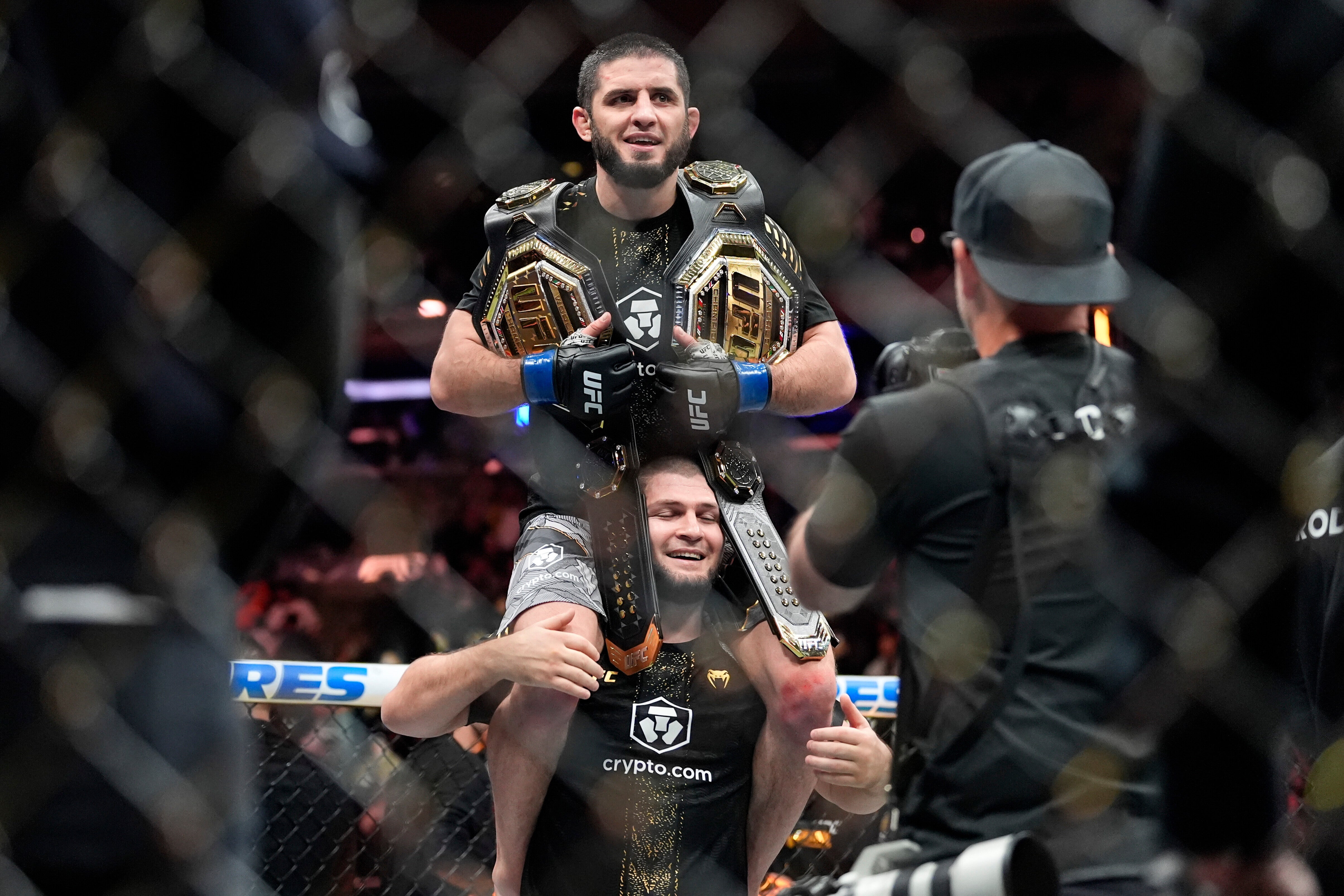 Khabib Nurmagomedov holds Islam Makhachev aloft with his two belts