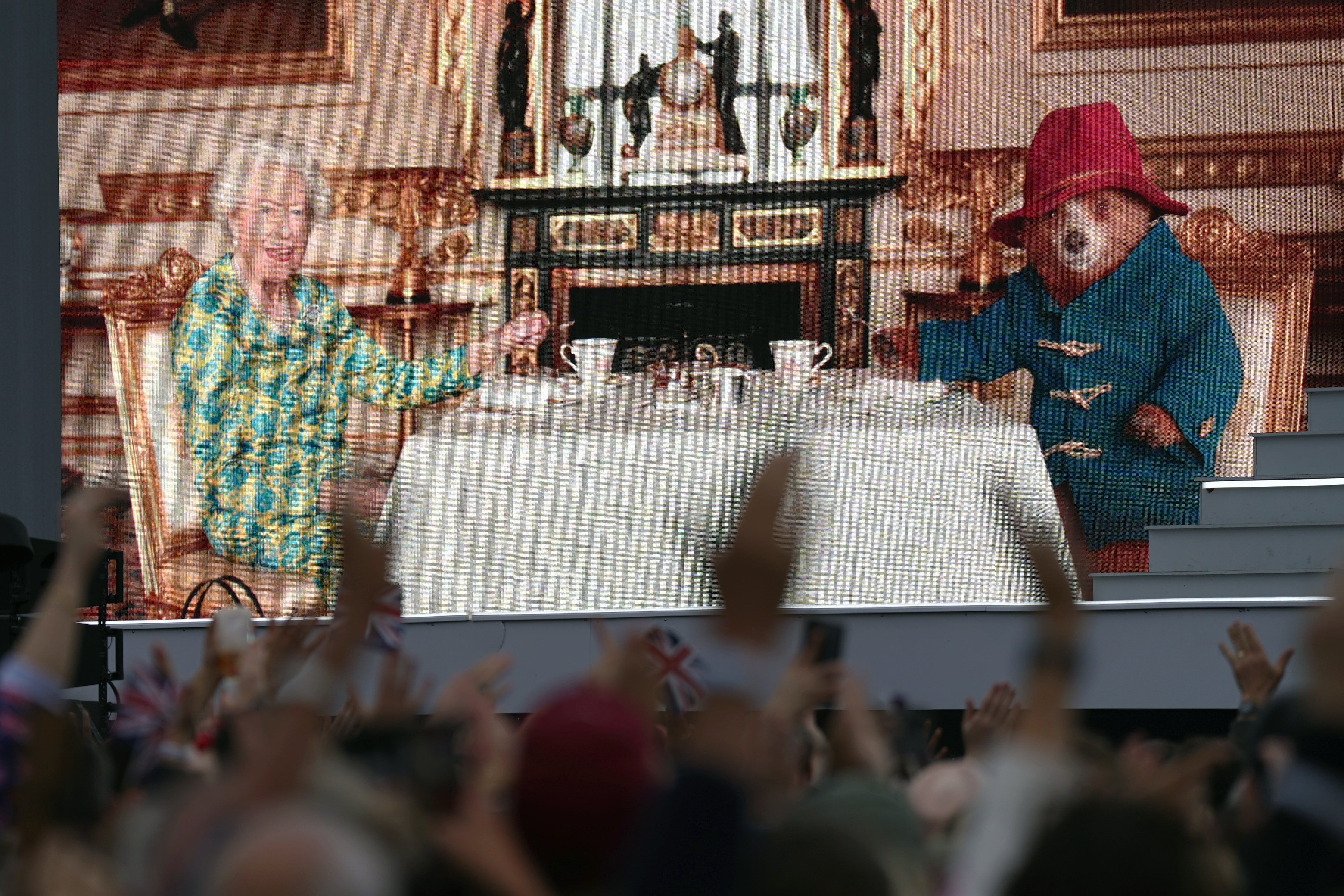 A crowd watching a film of Queen Elizabeth II having tea with Paddington Bear during the Platinum Party at the Palace in 2022 (Victoria Jones/PA)