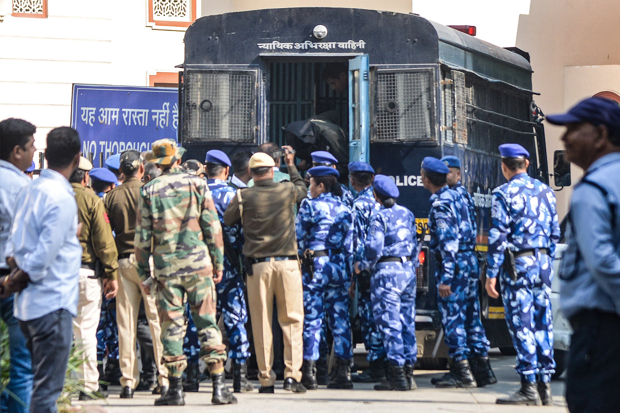 Security personnel escort car blast accused Amir Rashid Ali (C top) from a police vehicle, with his face covered in black cloth at the Patiala House Court