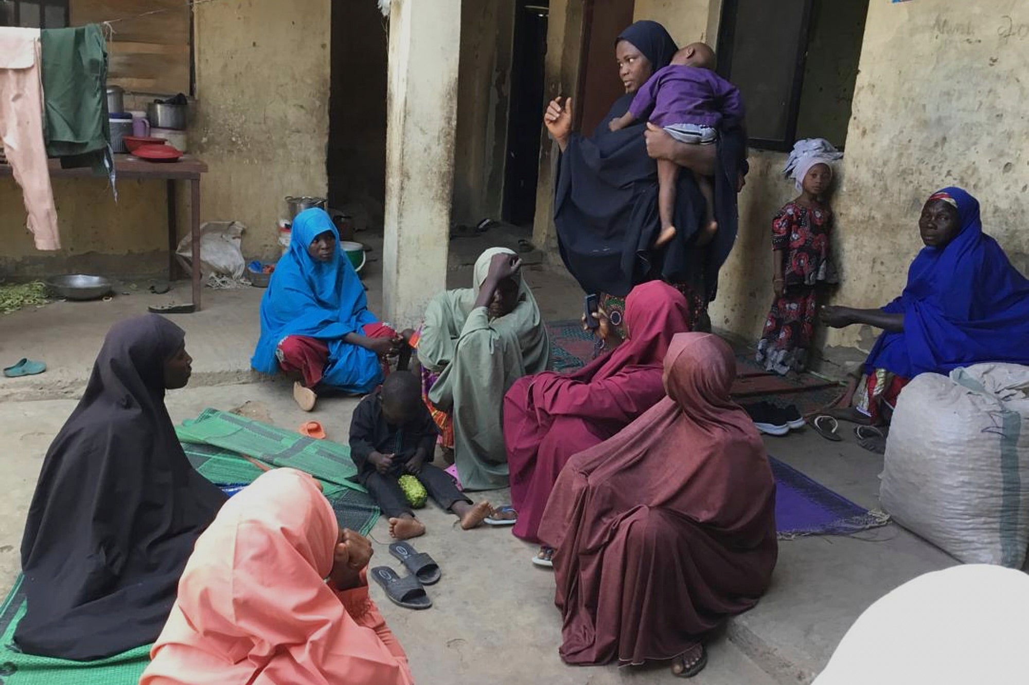 Amina Hassan, standing, wife of the vice principal of the Government Girls Comprehensive Secondary School, where gunmen on Monday attacked the school dormitory, abducted schoolgirls and killed her husband, with mourners, in Kebbi, Nigeria