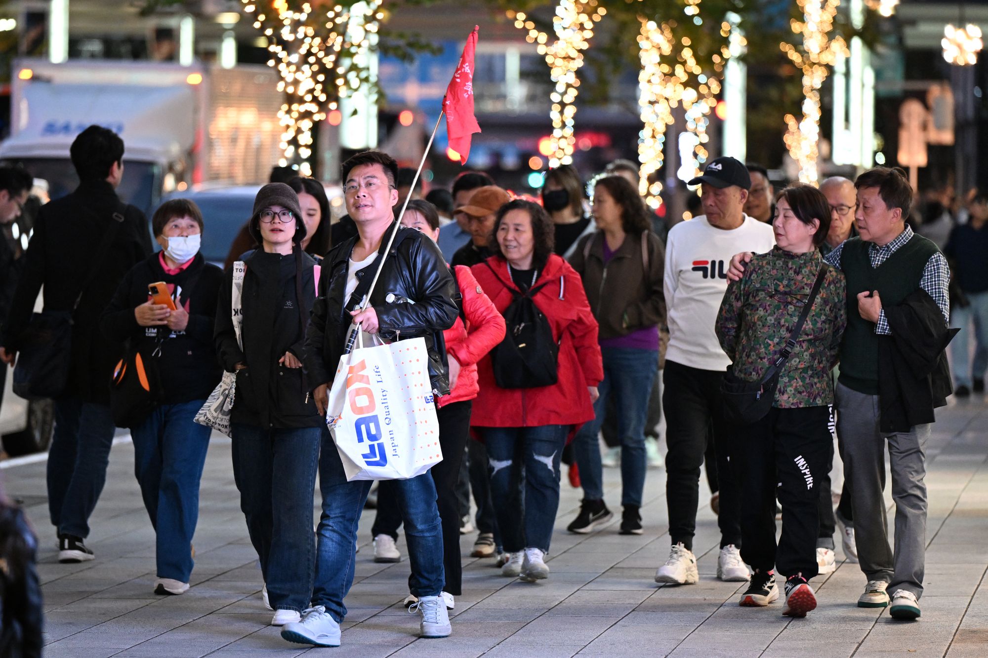 A Chinese tour group walks in the Ginza shopping district in Tokyo on 17 November 2025