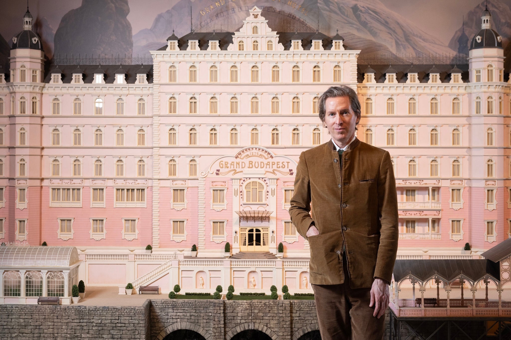 Wes Anderson poses with a miniature of the Grand Budapest Hotel from his 2014 film
