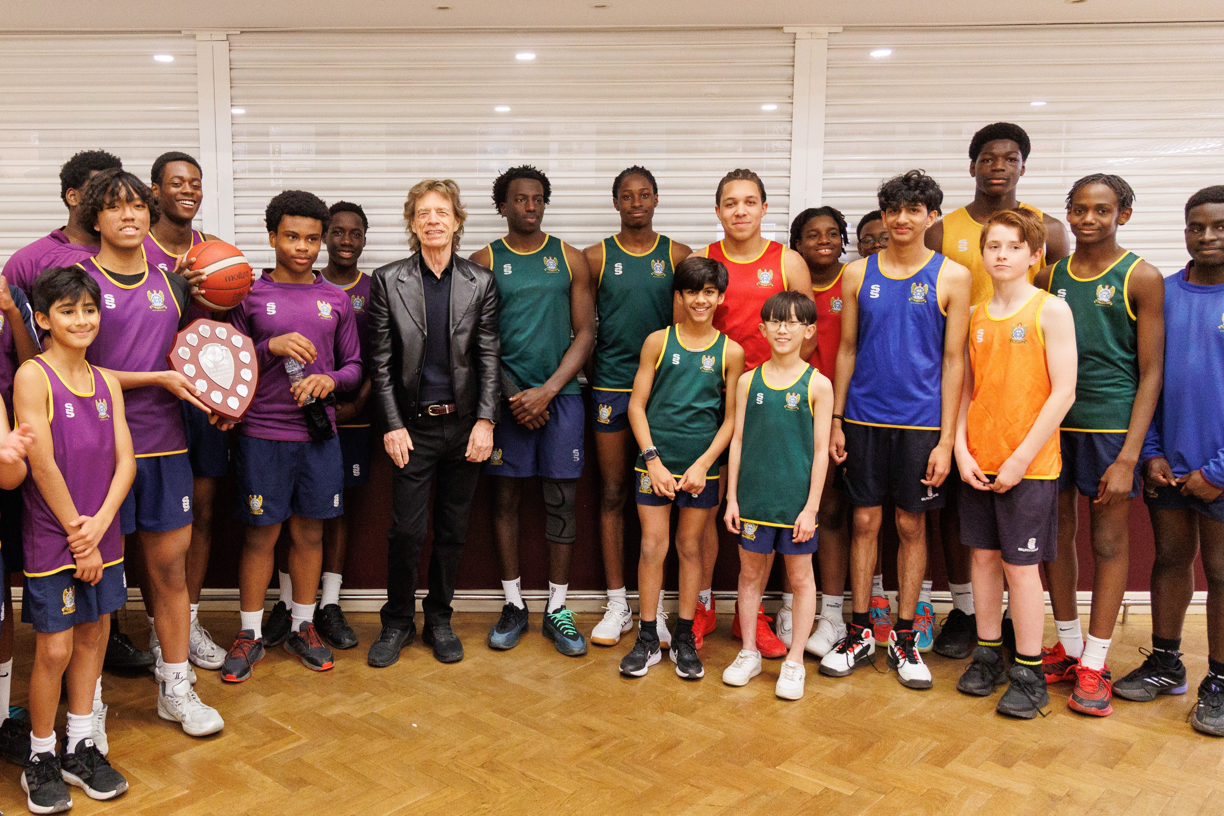 He posed alongside students after presenting a trophy to the current basketball team