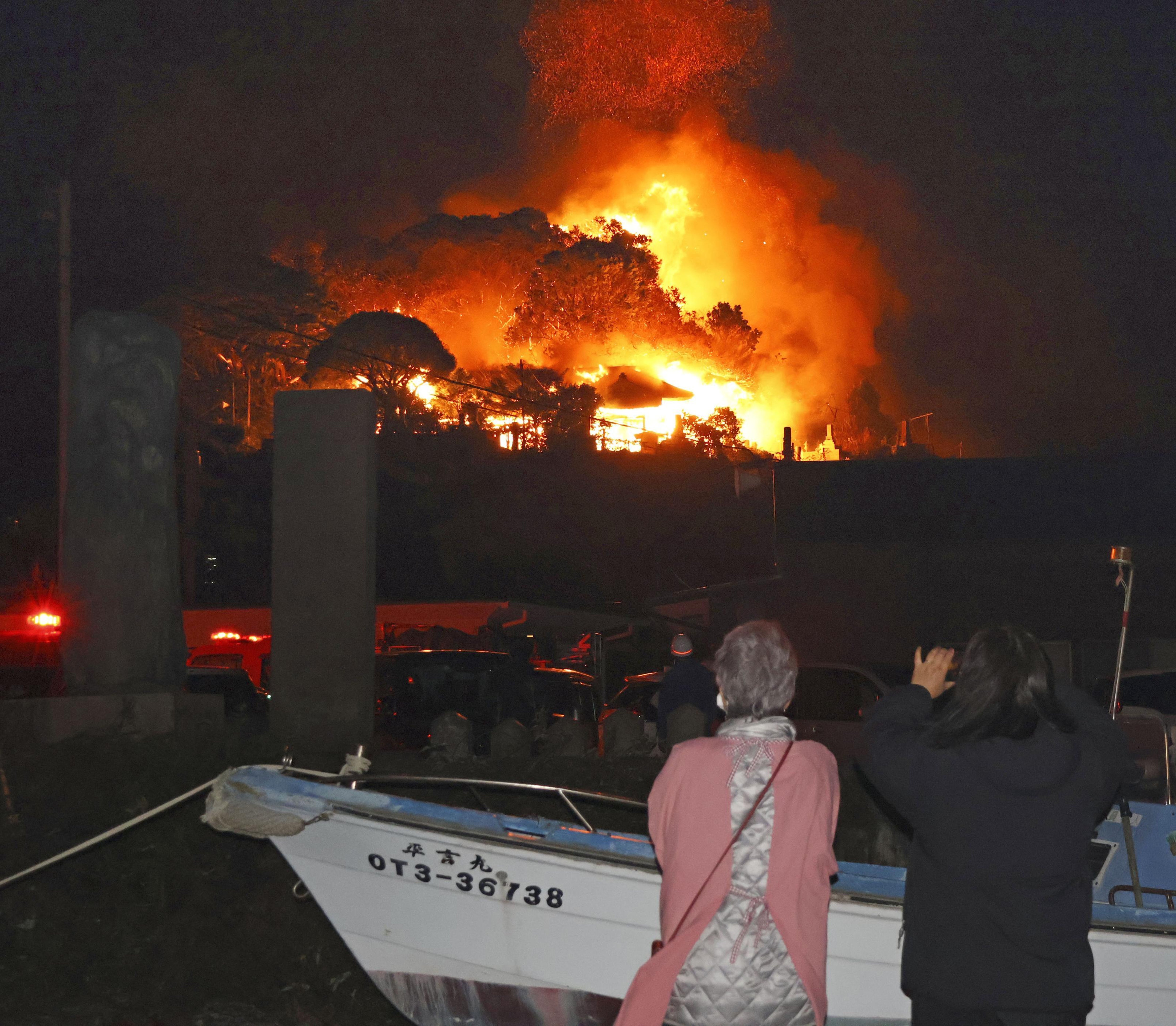 Residents watch flames rise from the site of a fire in Oita, southern Japan, on 18 November 2025