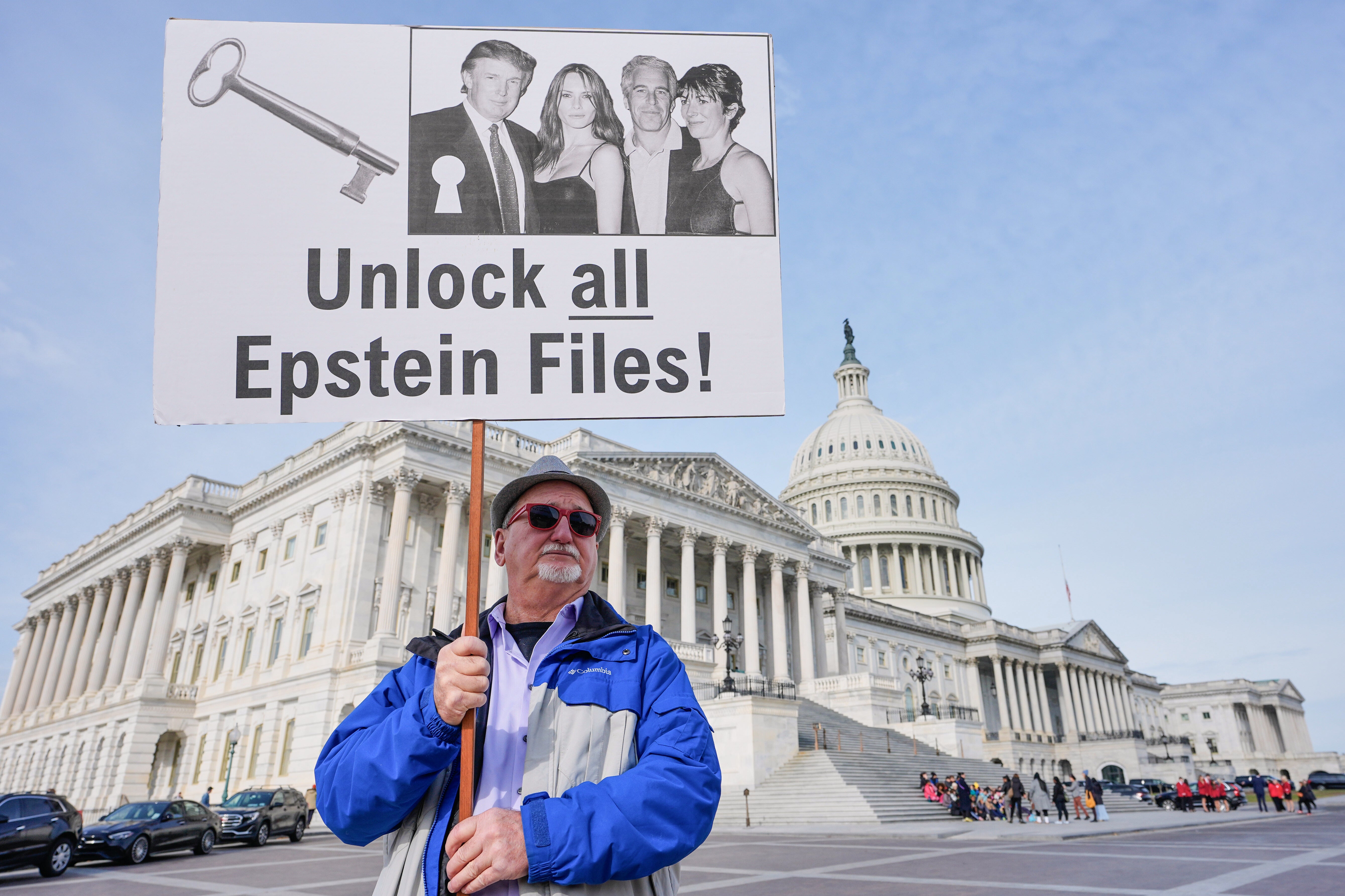 A man holds a sign protesting about the Epstein files