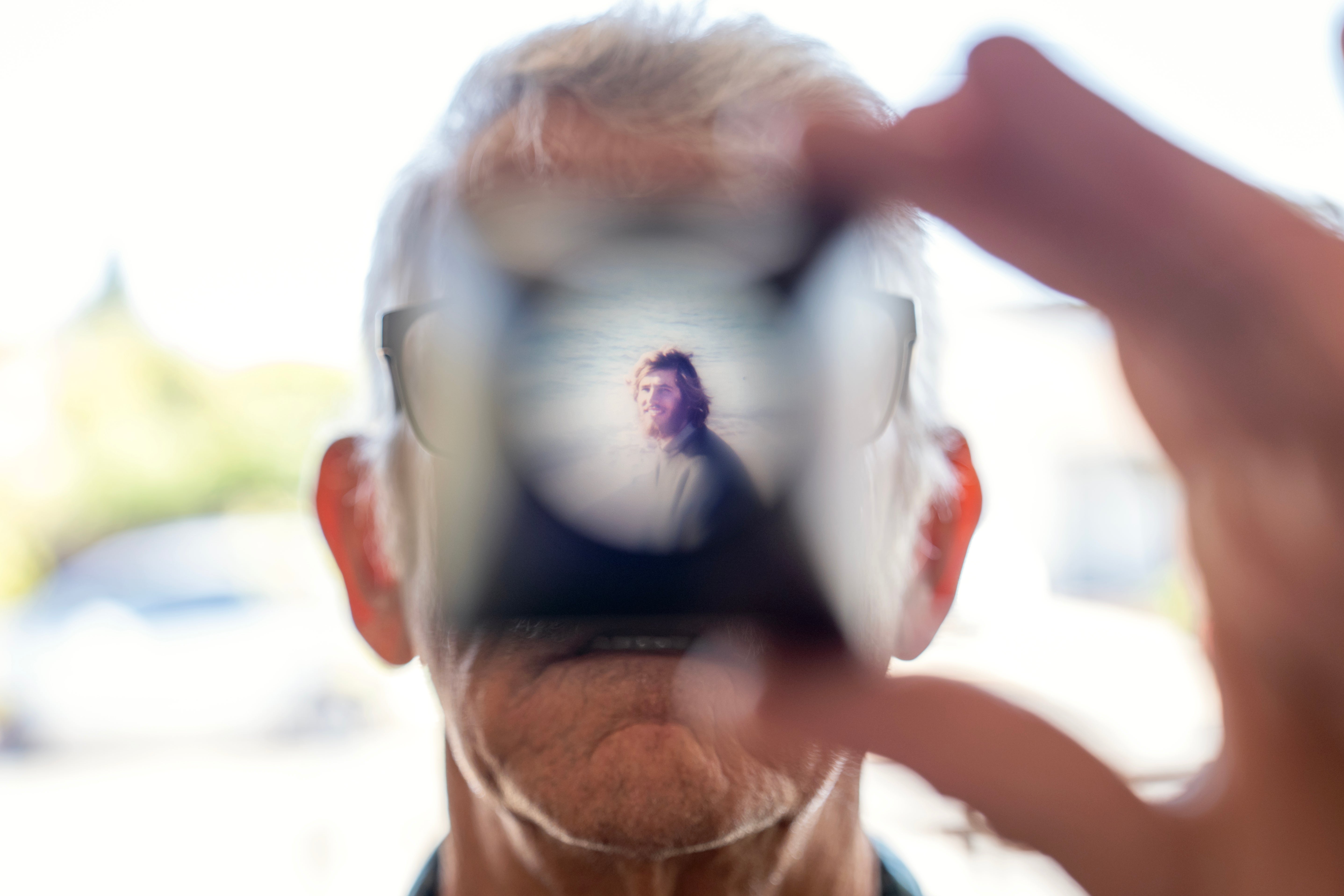 Christy Morrill, 72, who lost decades of memories to autoimmune encephalitis, holds up a viewfinder with a slide film of himself as a college student, Wednesday, Aug. 20, 2025, at his home in San Carlos, Calif. (AP Photo/David Goldman)