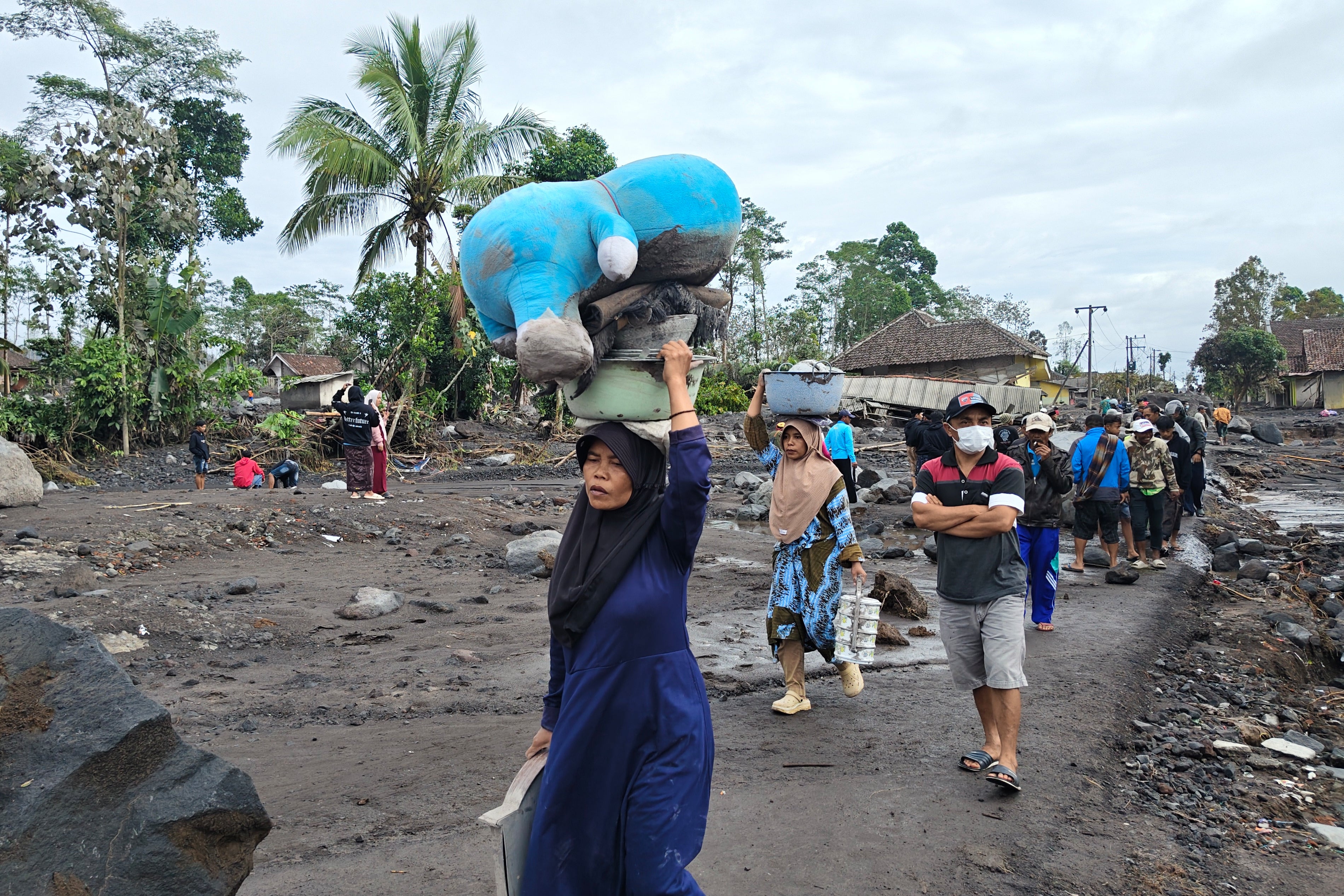 People carry their belongings as they evacuate their homes at a village affected by the eruption of Mount Semeru in Lumajang, East Java, Indonesia, Thursday, Nov. 20, 2025. (AP Photo/Wawan Sugiarto)