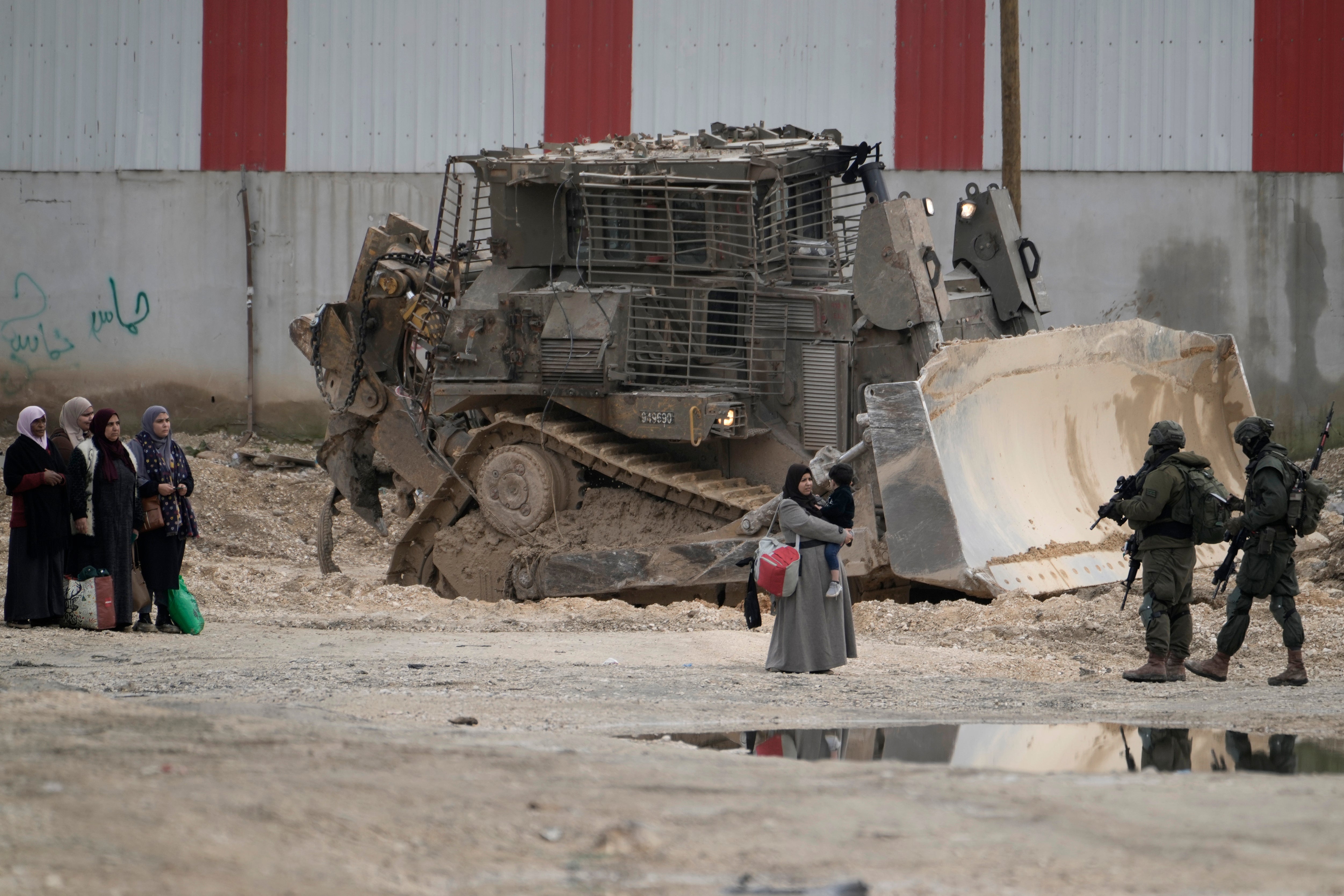 Israeli soldiers check the identification cards of Palestinians while they evacuate their homes in the West Bank refugee camp of Nur Shams, near Tulkarem, while the Israeli military operation continues in the area on 11 February
