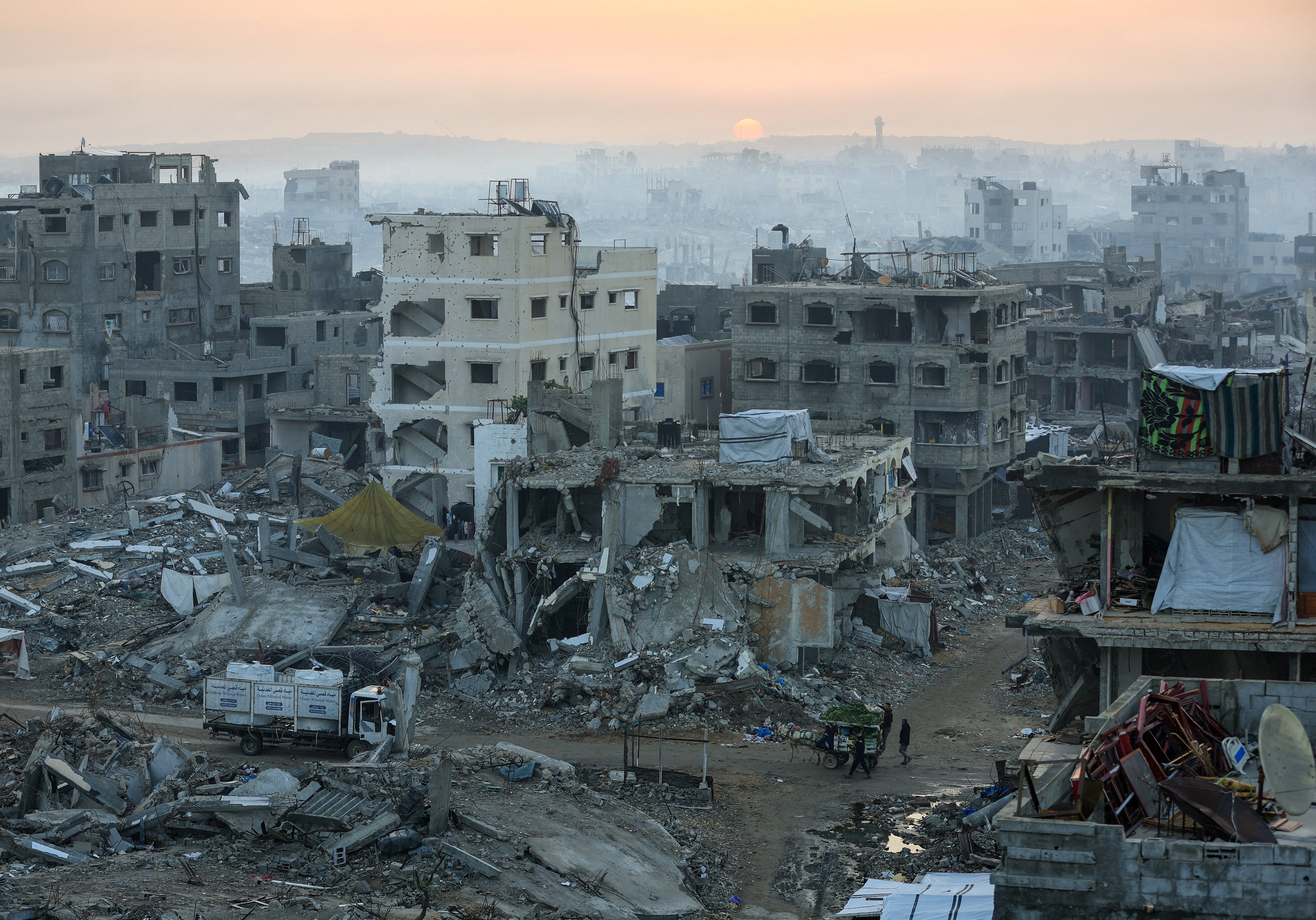 Palestinians walk past the rubble of destroyed buildings in Gaza City on 19 November 2025