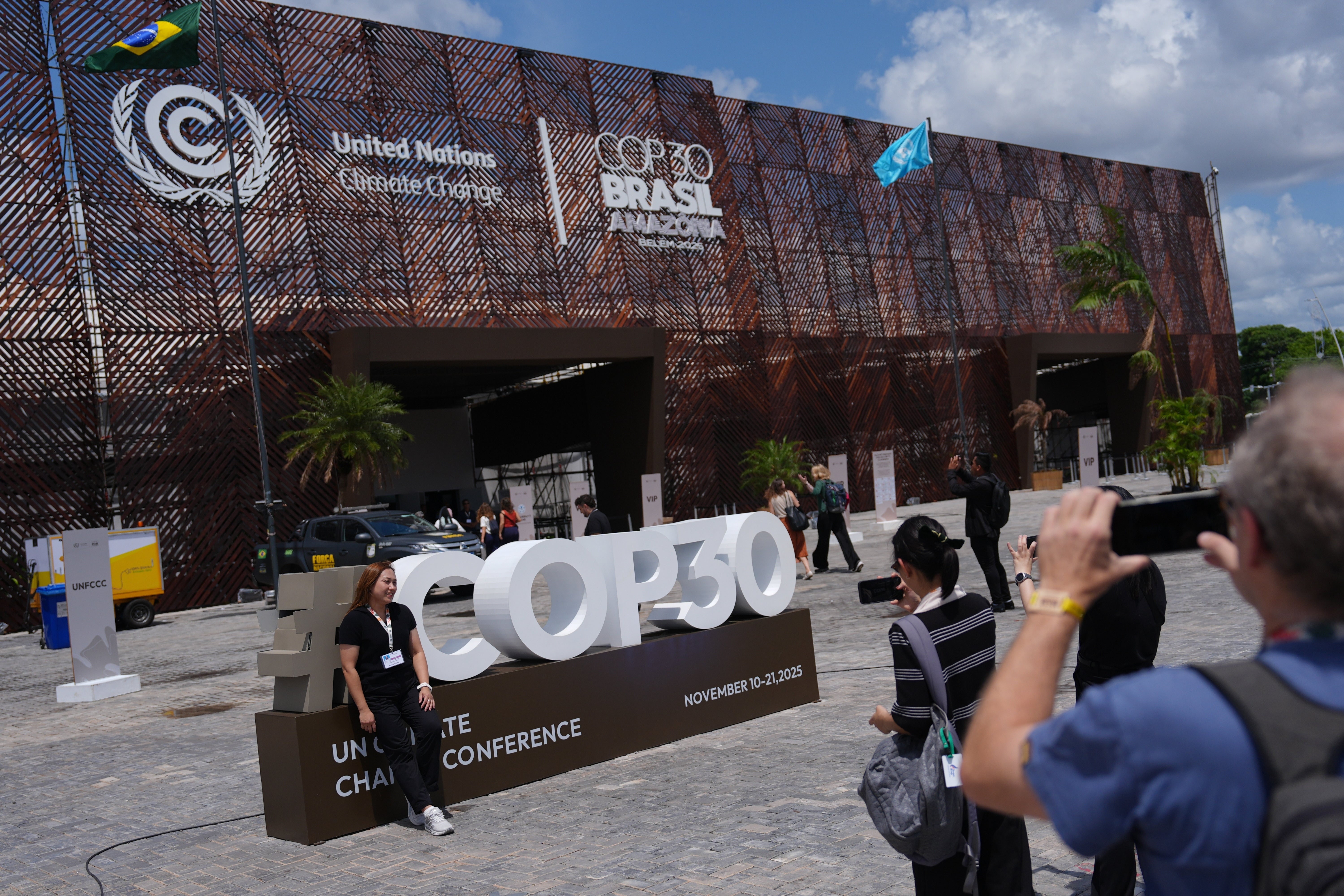 <p>People take pictures outside the venue for the Cop30 </p>
