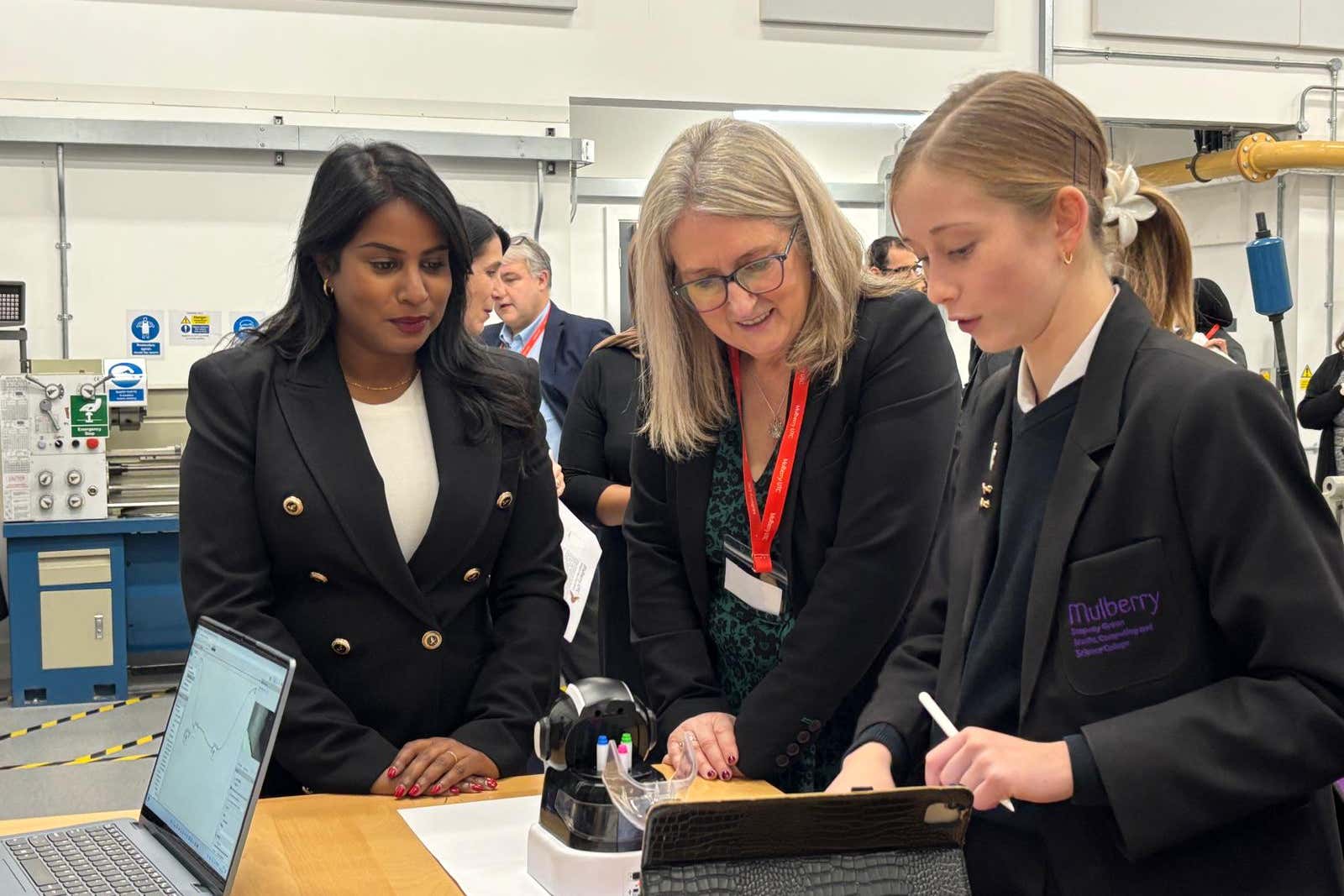 Skills minister Baroness Jacqui Smith, centre, and MP Uma Kumaran are shown a robot by a pupil at Mulberry UTC in east London (PA)