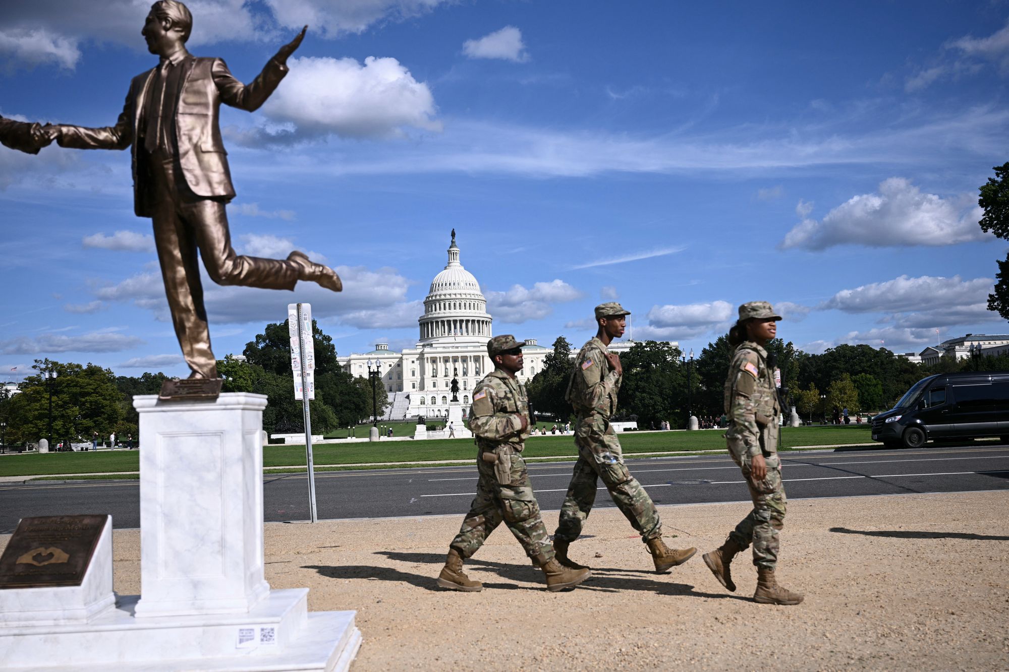 Members of the National Guard patrol the National Mall in Washington, DC, next to a statue depicting US President Donald Trump and Jeffrey Epstein holding hands near the US Capitol on October 2, 2025
