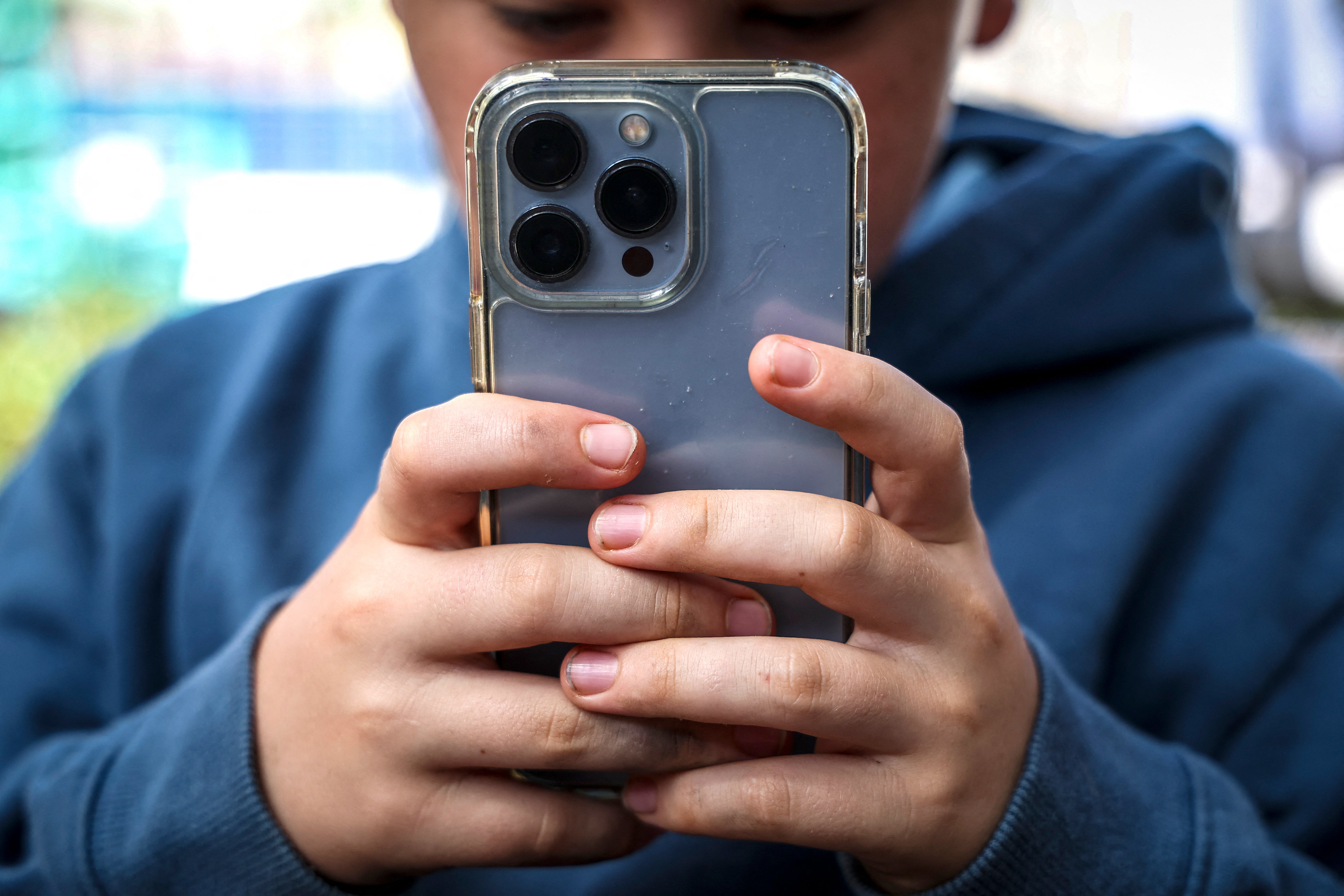 A 14-year-old boy posing at his home near Gosford as he looks at social media on his mobile phone