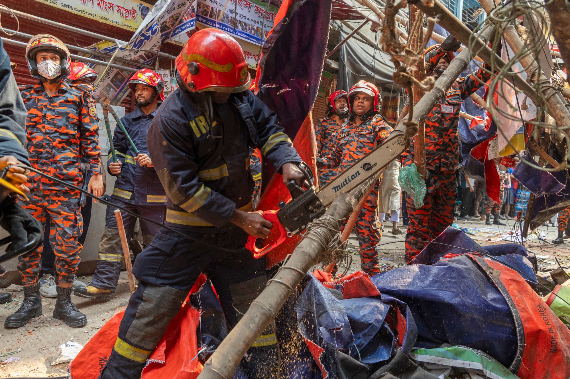 Rescue and fire officials cut building railings falling on the street to make way after an earthquake in Dhaka