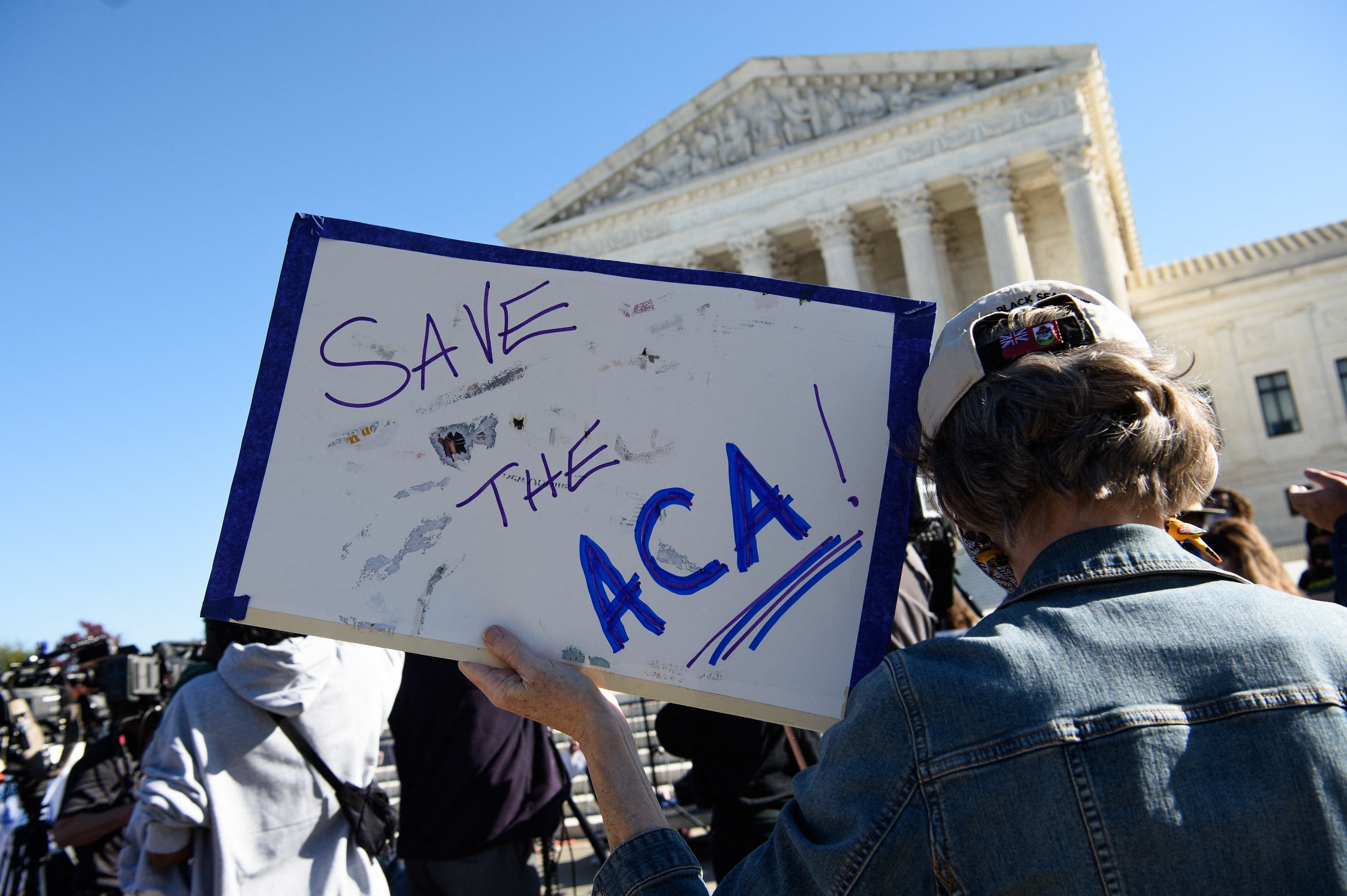 A demonstrator holds a sign in front of the US Supreme Court in Washington, DC, on November 10, 2020, as the high court opened arguments in the long-brewing case over the constitutionality of the 2010 Affordable Care Act.