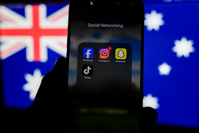 <p>Social media networking apps are displayed on a phone screen with the Australian flag displayed in the background </p>